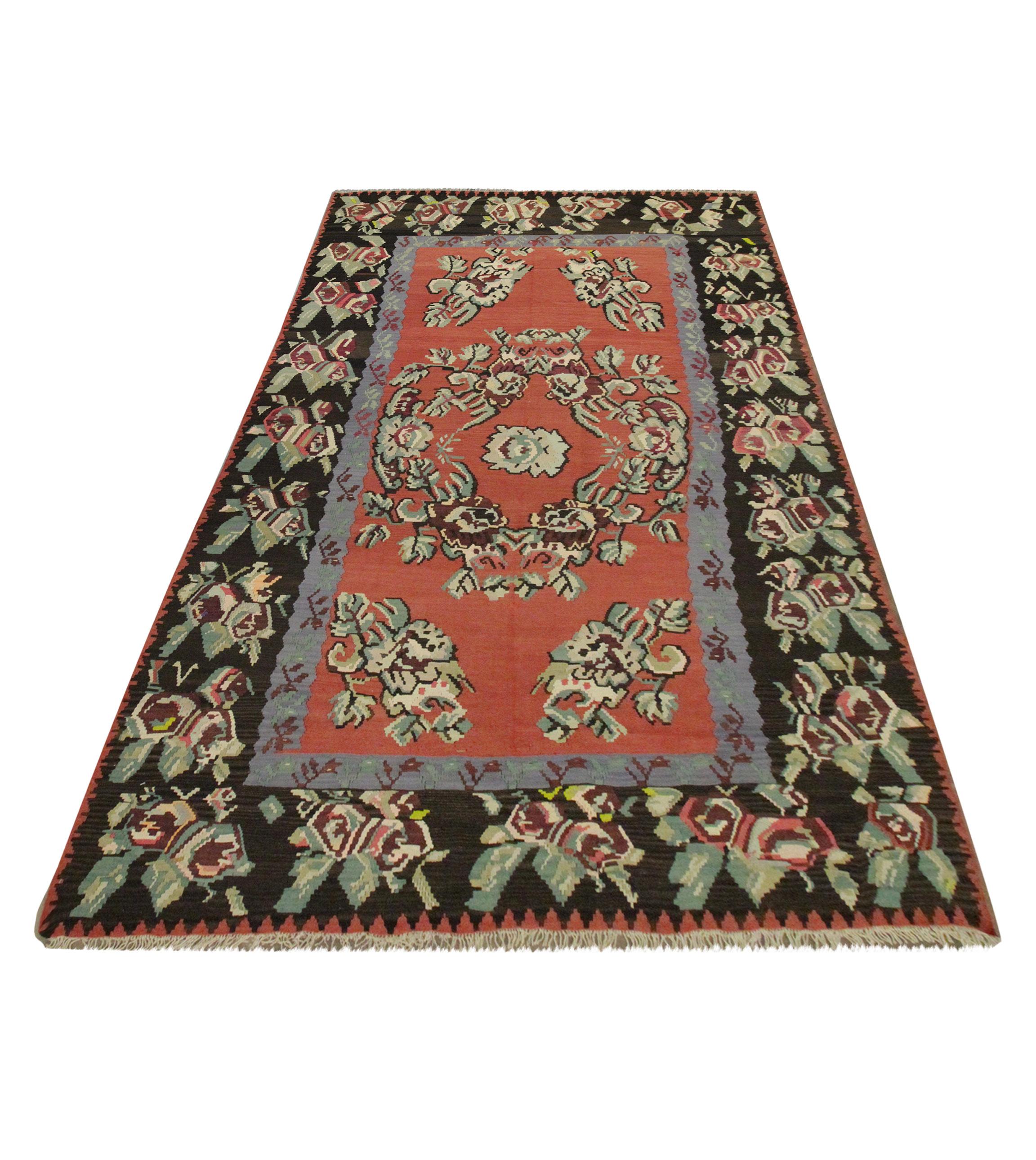 This small wool rug is a handmade Kilim woven in the early 20th century. This bold floral rug is has been woven with a rich red-rust field with asymmetrical floral design woven in green, brown and red accents. This is then framed by a tich border