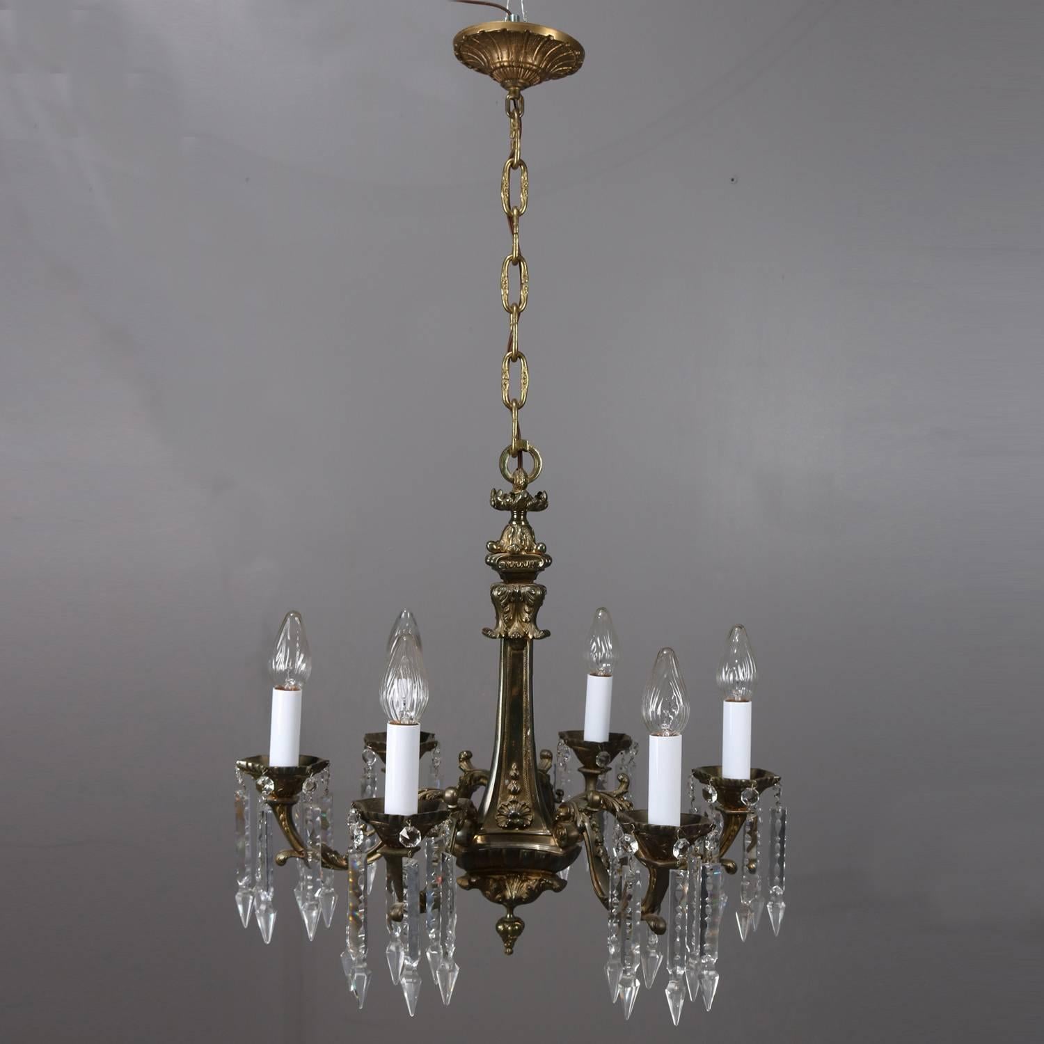 Traditional French Empire chandelier features faceted cast bronze base with floral and foliate decoration, five foliate form arms terminating in candle lights with hanging cut crystal prisms, newly re-wired, circa 1920

Measures: 20