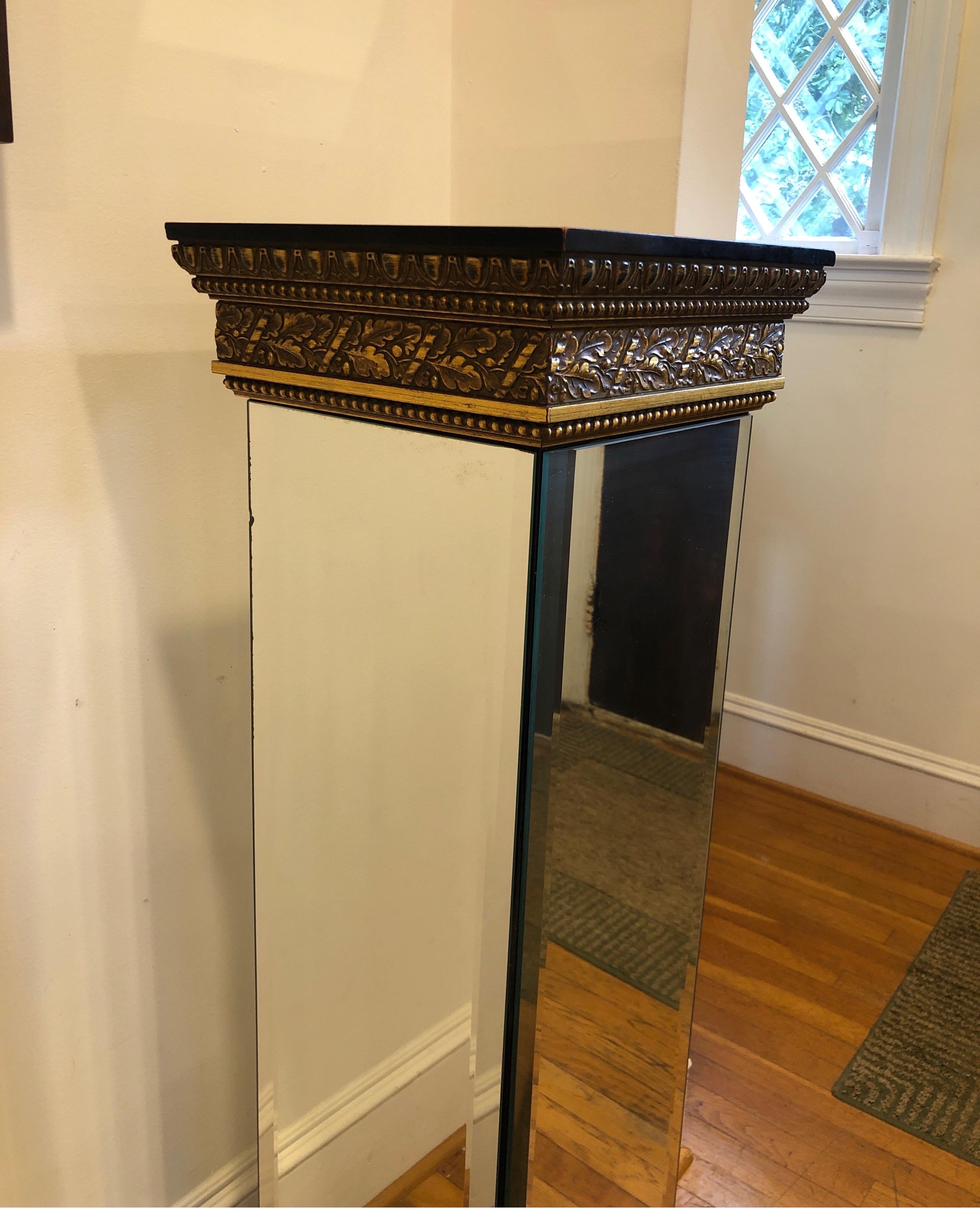 Traditional mirrored pedestal table constructed from beveled mirror and gold gilded wood. 
Top is mirrored with a small circle cut out. See images. 

Measures 45.5 H x 13 W x 13 D 

No cracks. Some minor signs of age and chips on wood.