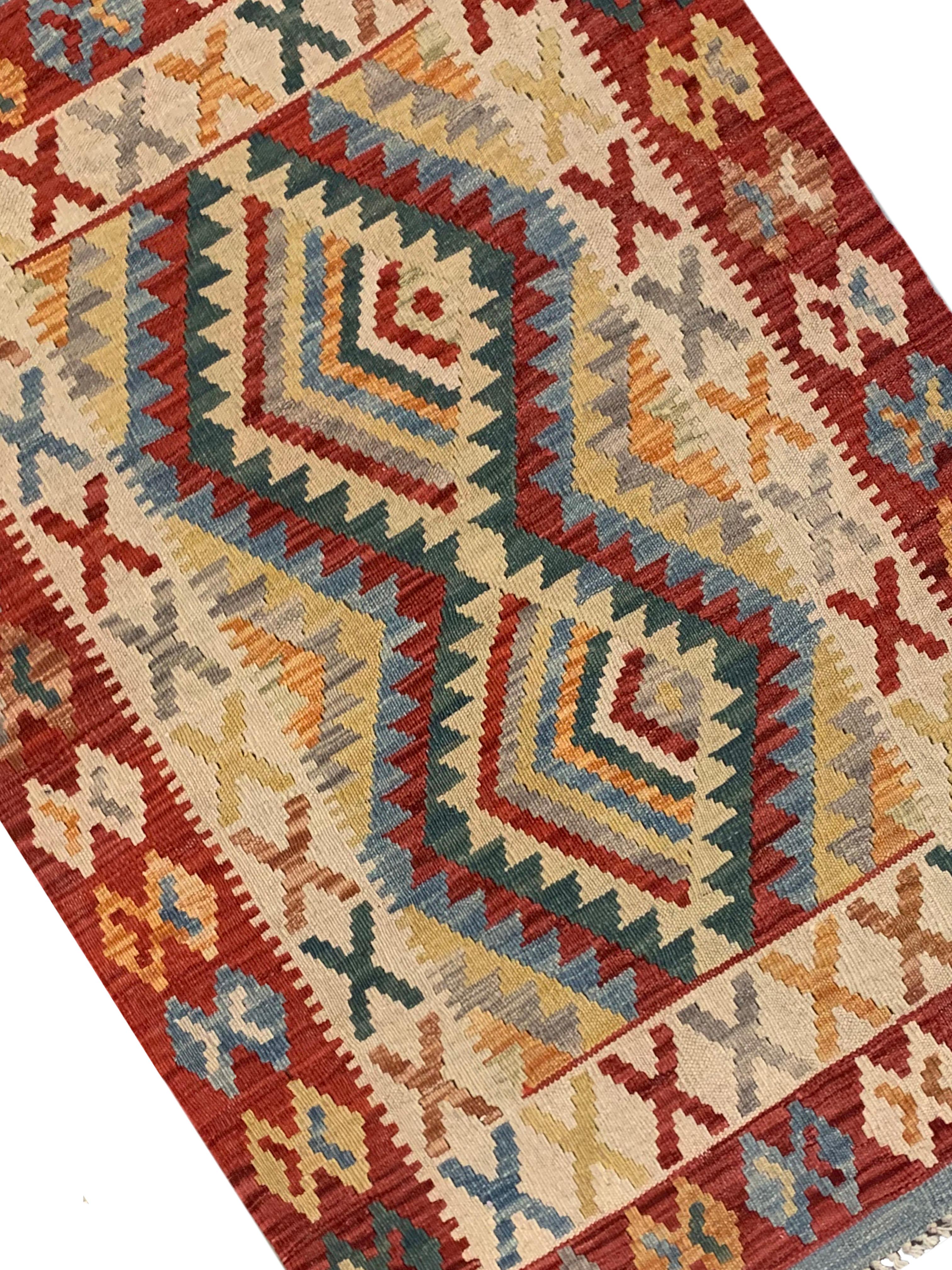 This fine wool area rug was woven by hand in the early 2000s. The central design features a bold geometric pattern with two large medallions that have been woven with a decorative surrounding design and border. Woven in green, beige, red and blue