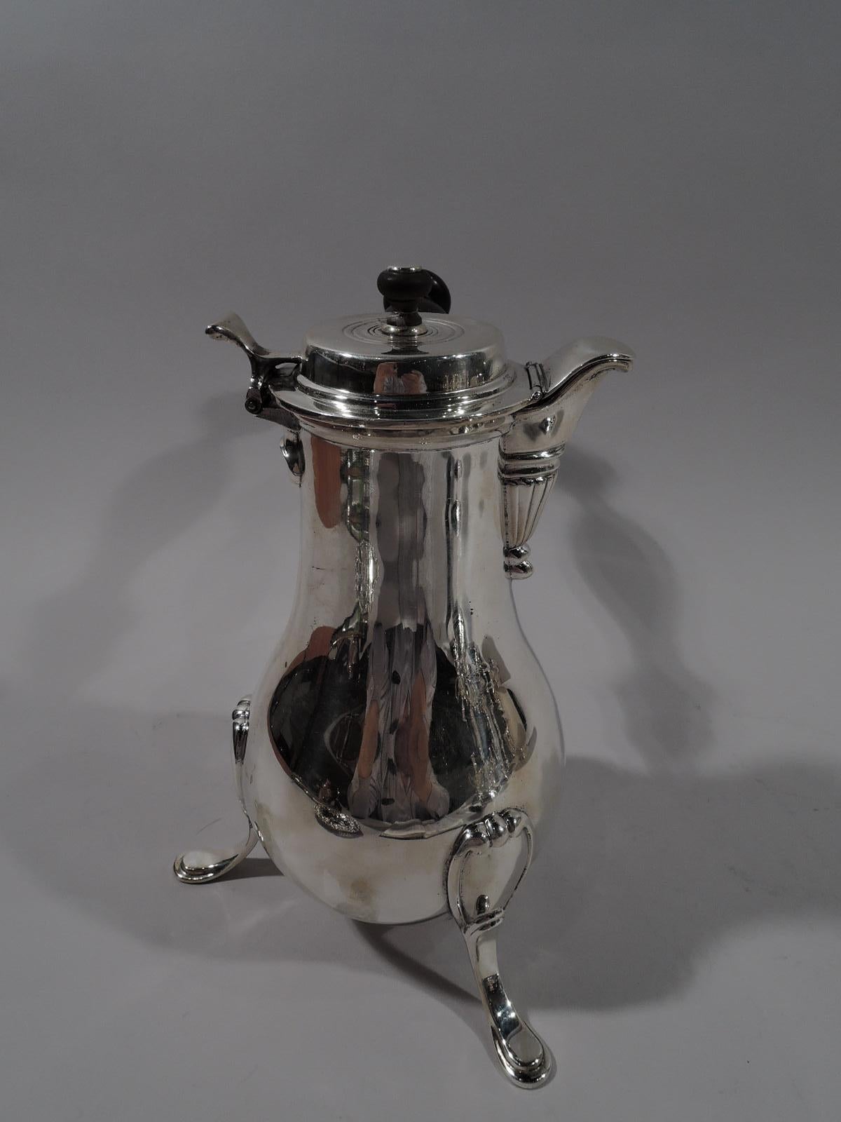 Georgian sterling silver chocolate pot. Made by Howard & Co. in New York in 1903. Baluster body on 3 scroll-mounted hoof supports. Turned and stained-wood handle. Cover hinged and raised with thumb-rest and hinged spout CAP. Spout V-Form and fluted.