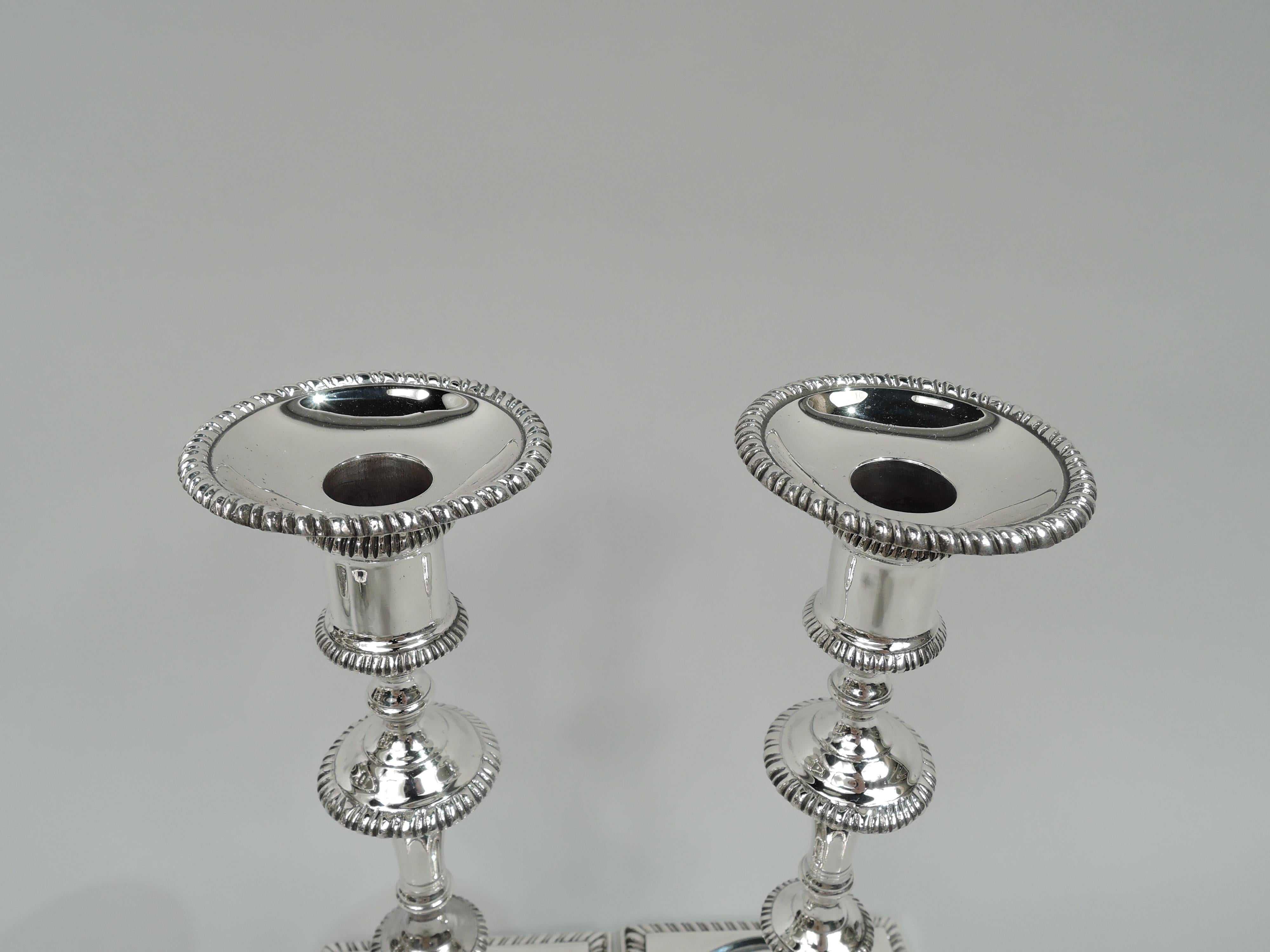 Traditional Georgian-style sterling silver candlesticks, circa 1950. Each: spool socket with detachable bobeche on knopped and flanged shaft; foot square. Gadrooned rims. Fully marked including stamp for Prill Silver Co., Inc. a New York maker