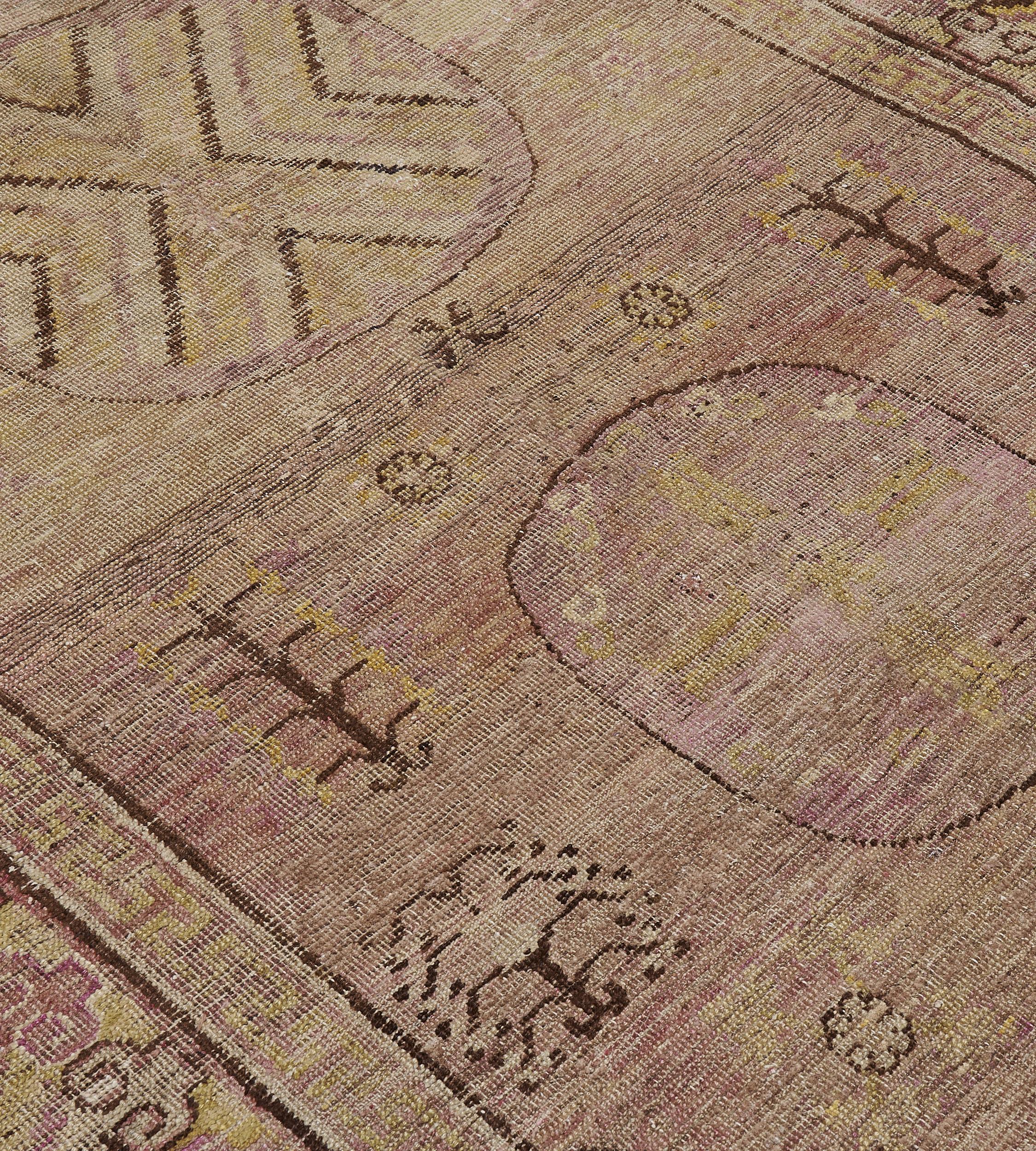 Dieser traditionelle, handgewebte Samarkand-Khotan-Teppich hat ein schattiertes, goldbraunes Feld mit spärlich gesprühten Glückssymbolen, die eine dreifache Säule aus Rundmedaillons einschließen, die von chinesischen geometrischen Zwickeln umgeben