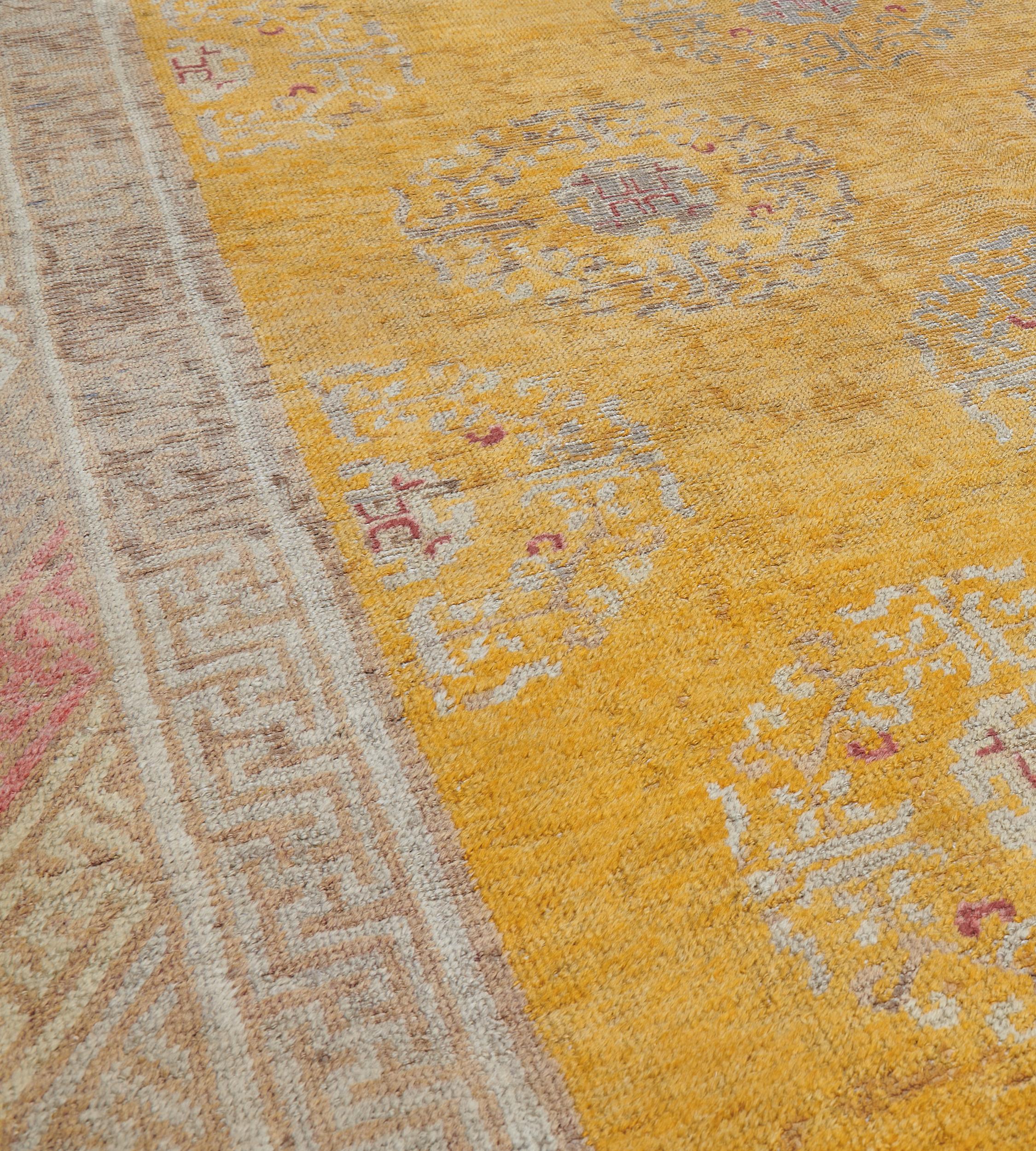 Dieser traditionelle, handgewebte Samarkand-Khotan-Teppich hat ein warmes, goldenes Gesamtfeld mit diagonalen Reihen traditioneller chinesischer geometrischer Kränze in einer raffinierten Doppelschlüsselmuster-Bordüre.