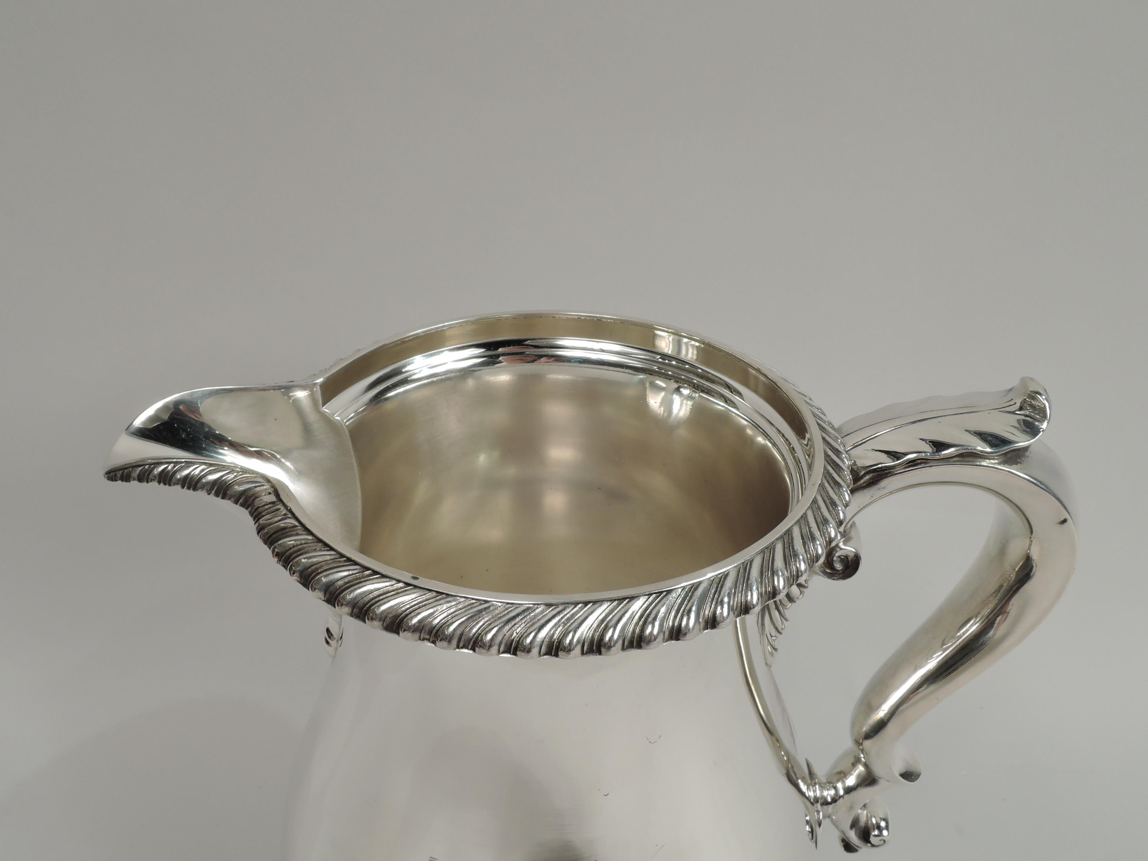 Kensington sterling silver water pitcher. Made by Gorham in Providence in 1947. Baluster with leaf-capped double-scroll handle, v-lip spout, and round and stepped foot. Gadrooned rim. Traditional Georgian with nice heft. Fully marked including