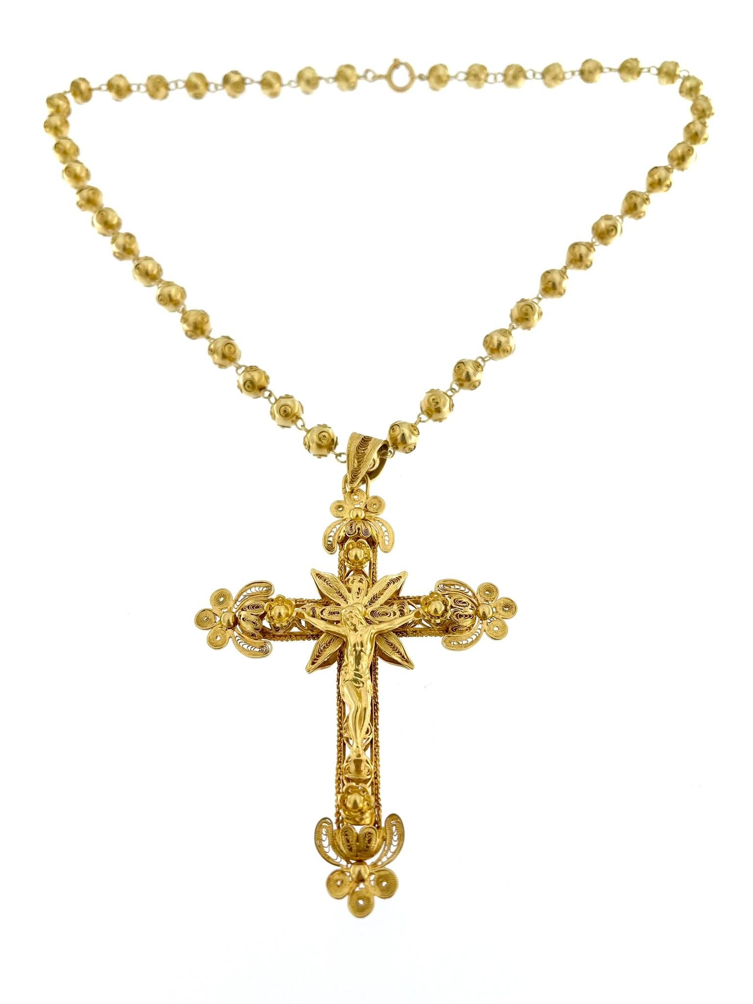This traditional Portuguese crucifix with chain is a magnificent representation of Portuguese craftsmanship, characterized by intricate details and a rich cultural heritage. Crafted from 19 karat yellow gold, this piece exudes warmth and luxury,