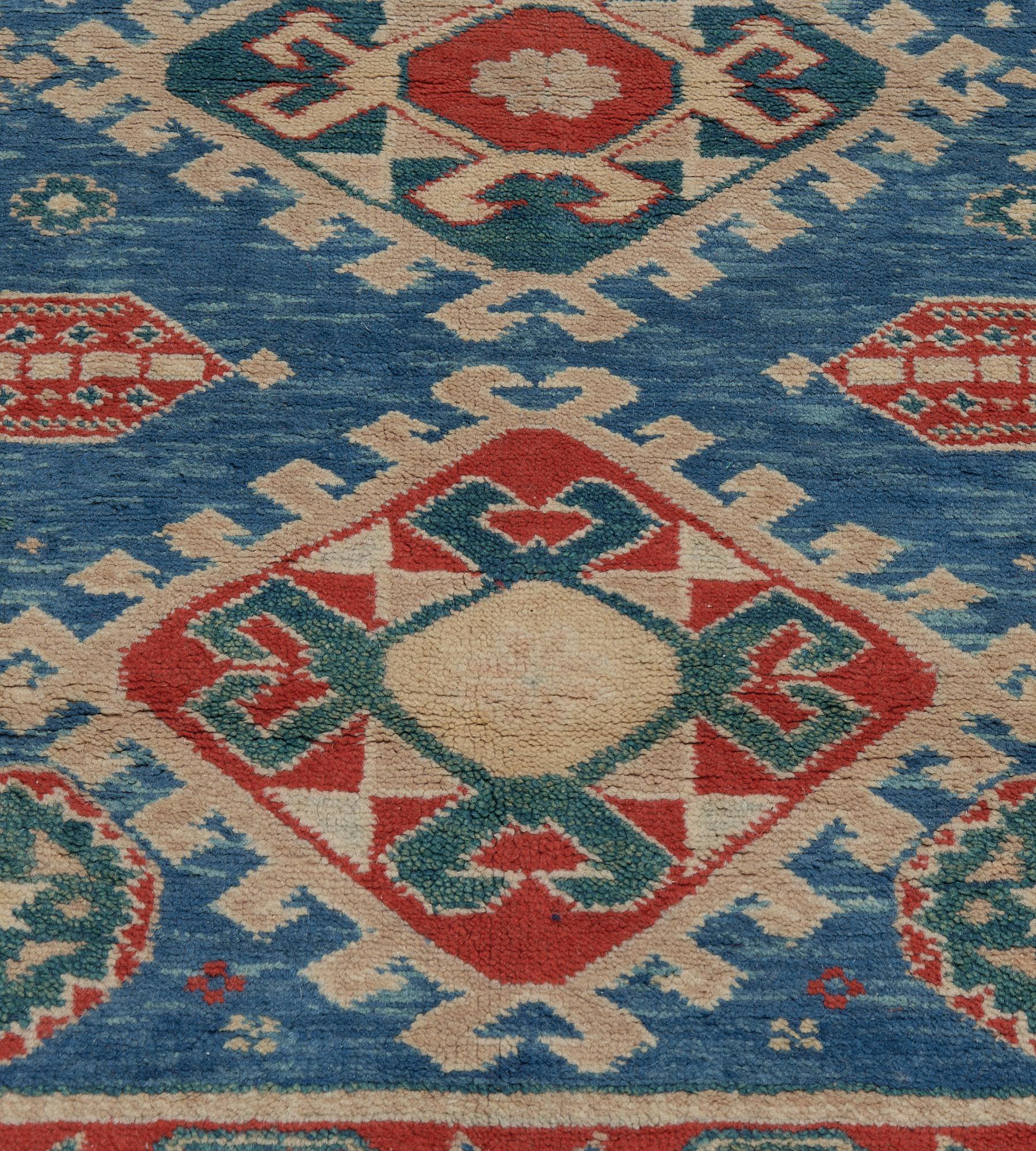 This traditional hand-woven Turkish rug has a vibrant blue field enclosing a central column of three serrated medallions, in a red floral vine border, between a diamond accented outer stripe and simple ivory inside stripe.