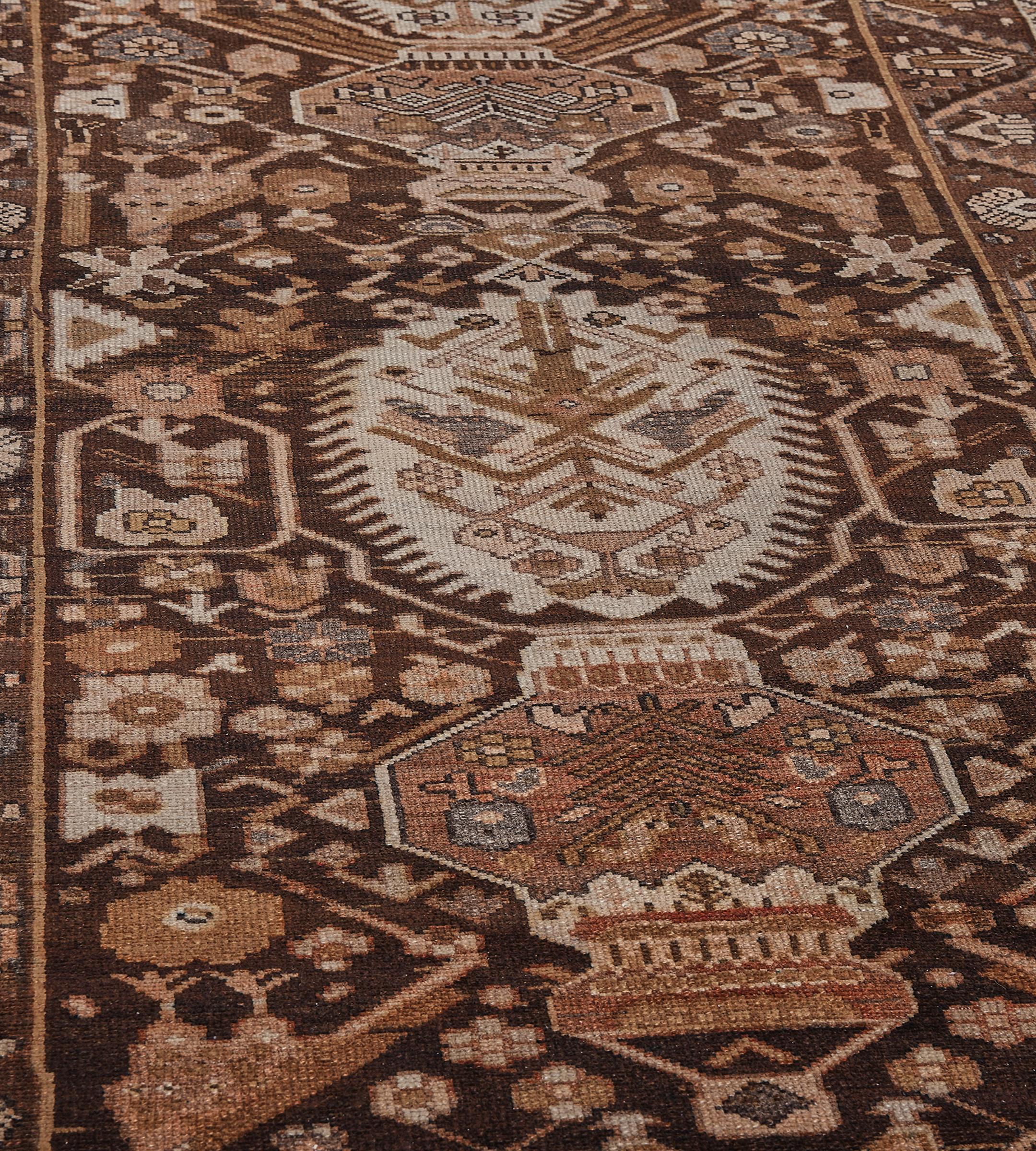 Dieser traditionelle, handgewebte persische Bachtiari-Teppich hat ein schattiertes, schokoladenbraunes Feld mit einer Fülle von geometrischen Blumenspritzern und abgewinkelten Ranken, die breite, abgewinkelte Blumentöpfe mit gezackten, geometrischen