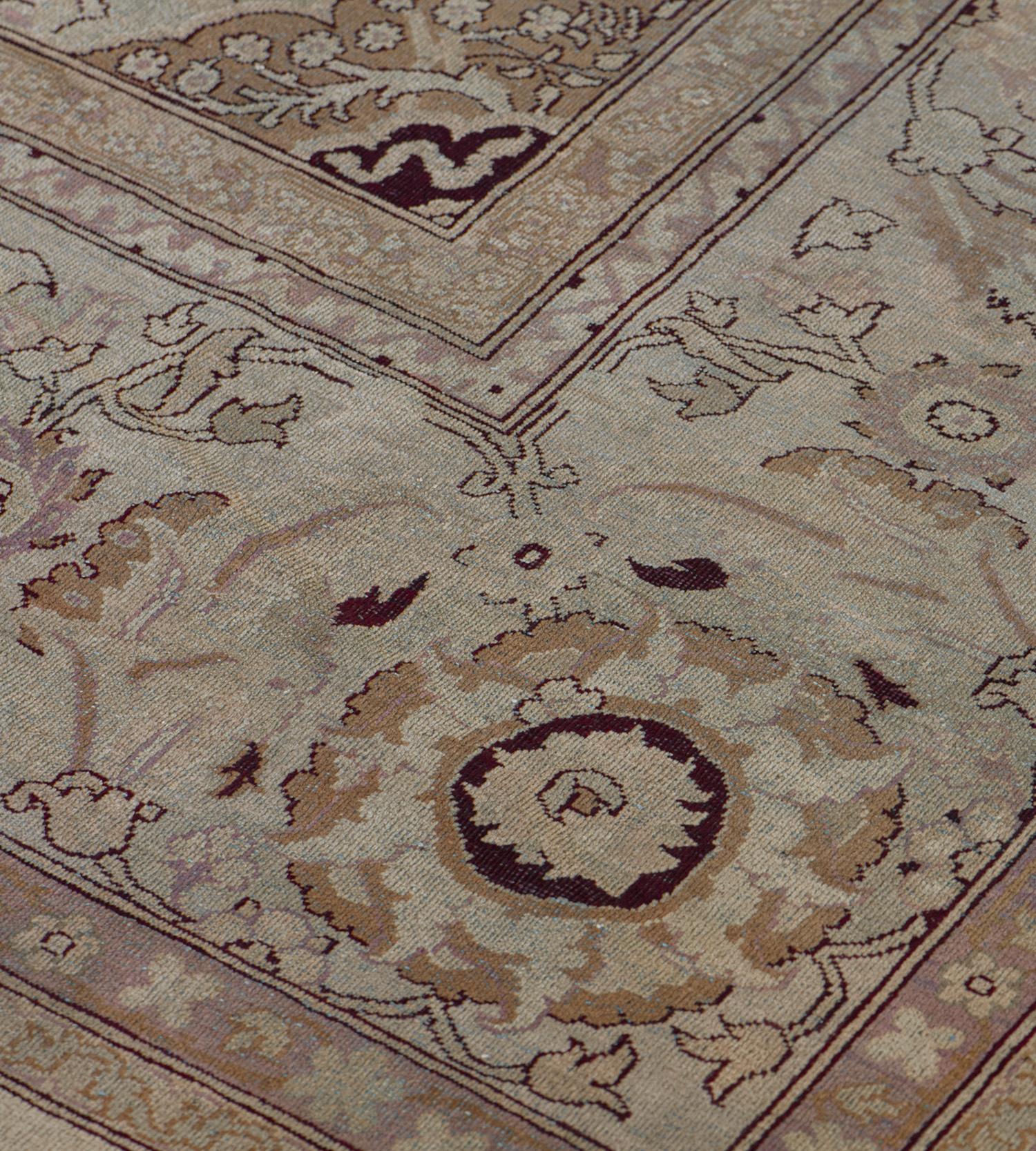 Ce tapis indien traditionnel d'Agra, tissé à la main, présente un champ crème ivoire avec des palmettes tonales formant des vignes florales sinueuses, entourant un médaillon arabesque tonique et des écoinçons similaires, dans une bordure de