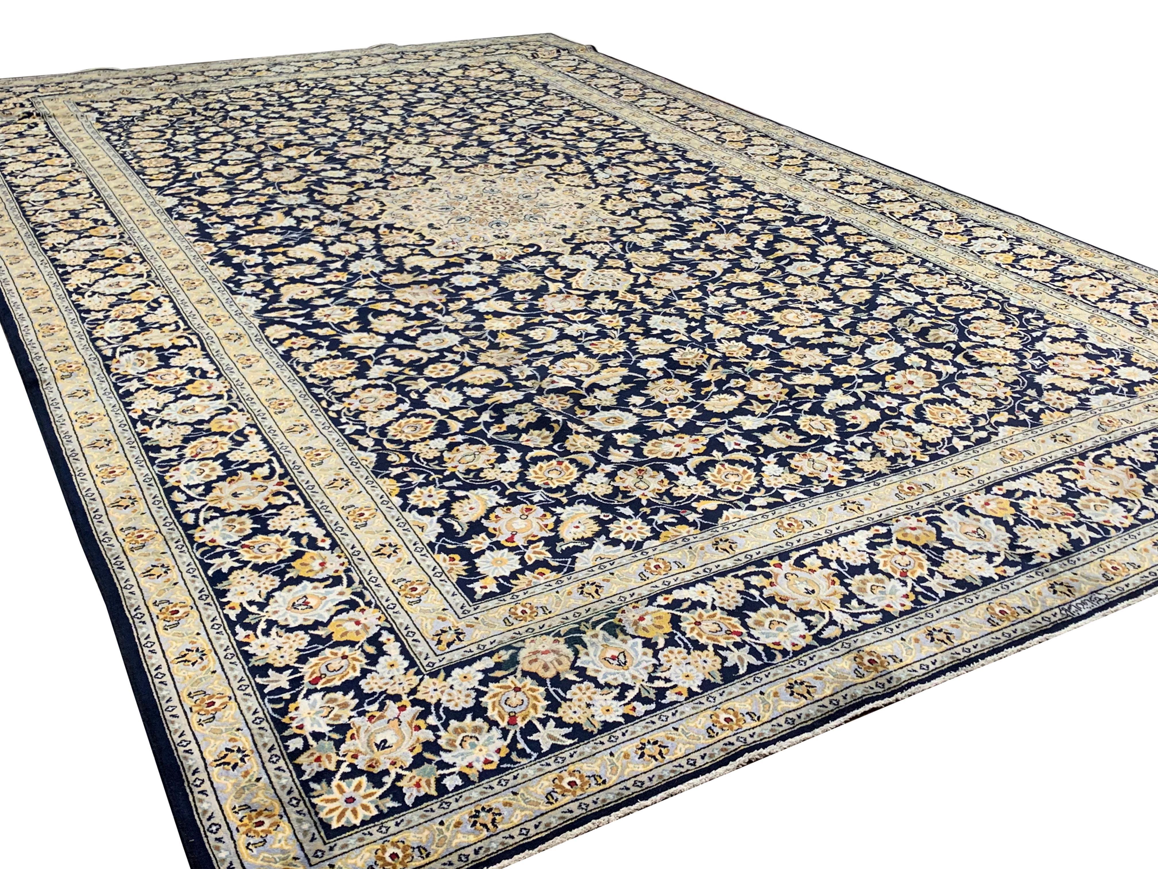 This fine wool area rug has been woven with a traditional oriental design featuring an intricate central medallion with a symmetrical, floral surrounding design. The design has been woven with a deep blue background with accents of cream, beige and