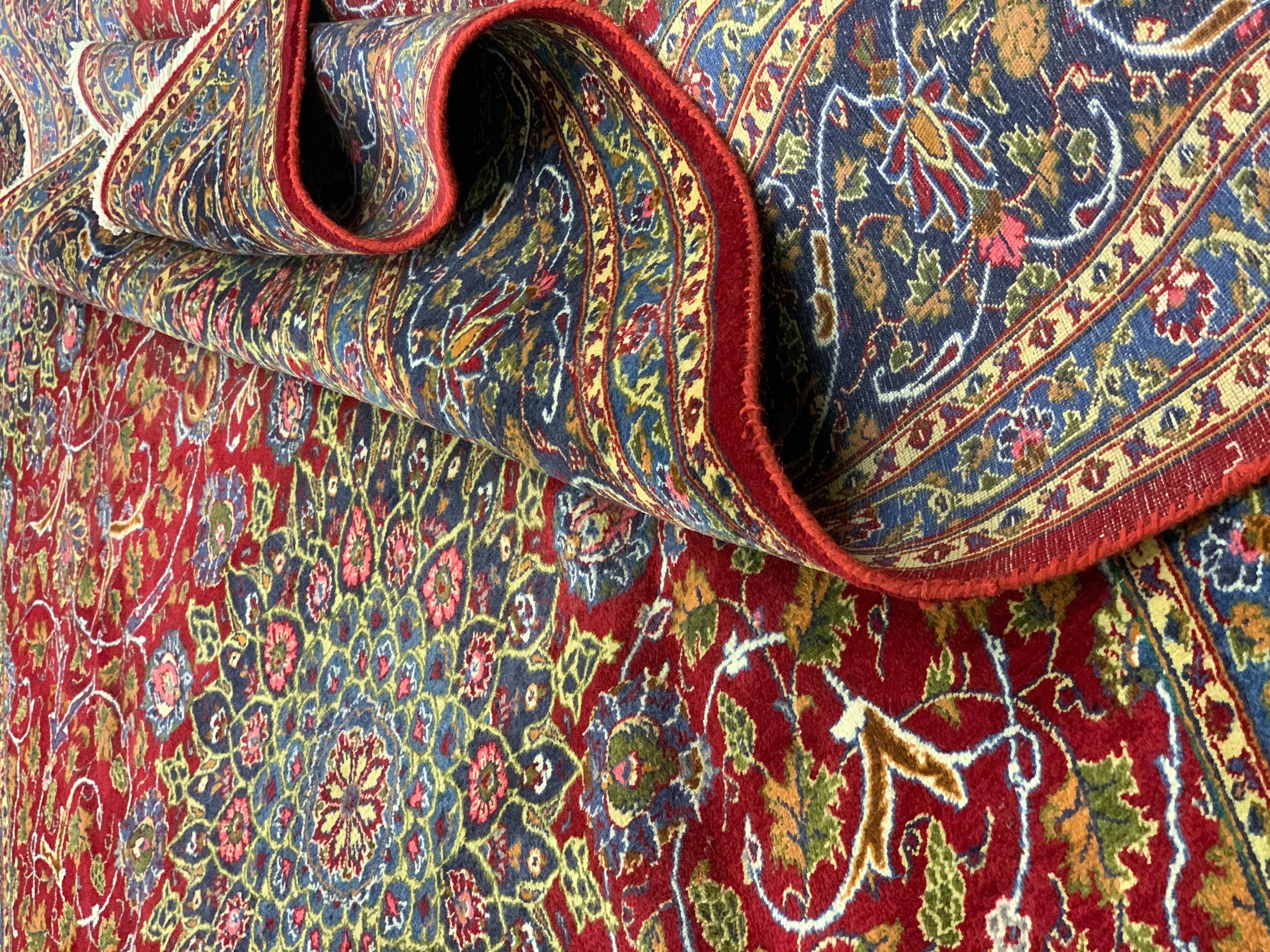 This bold wool carpet has been woven with a rich red background that has been decorated with a traditional medallion design. Symmetrically woven with botanical patterns including flowers and leaves that elegantly cascade around the intricate