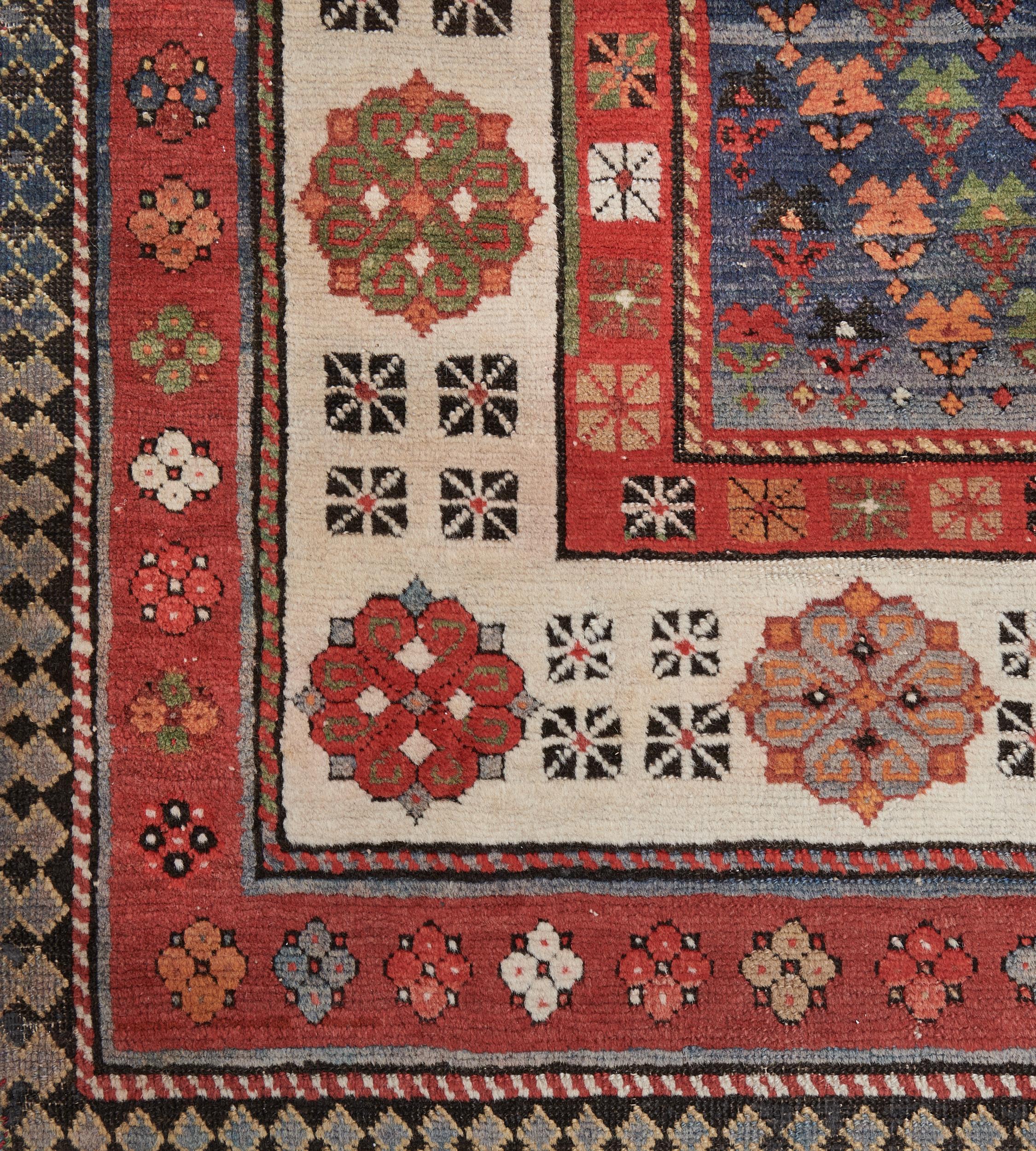 Dieser traditionelle, handgewebte kaukasische Talysh-Teppich hat ein schattiertes, tiefblaues Feld mit abwechselnd polychromen, diagonalen, geometrischen Blumenmotiven in einer elfenbeinfarbenen Rosettenbordüre zwischen polychromen