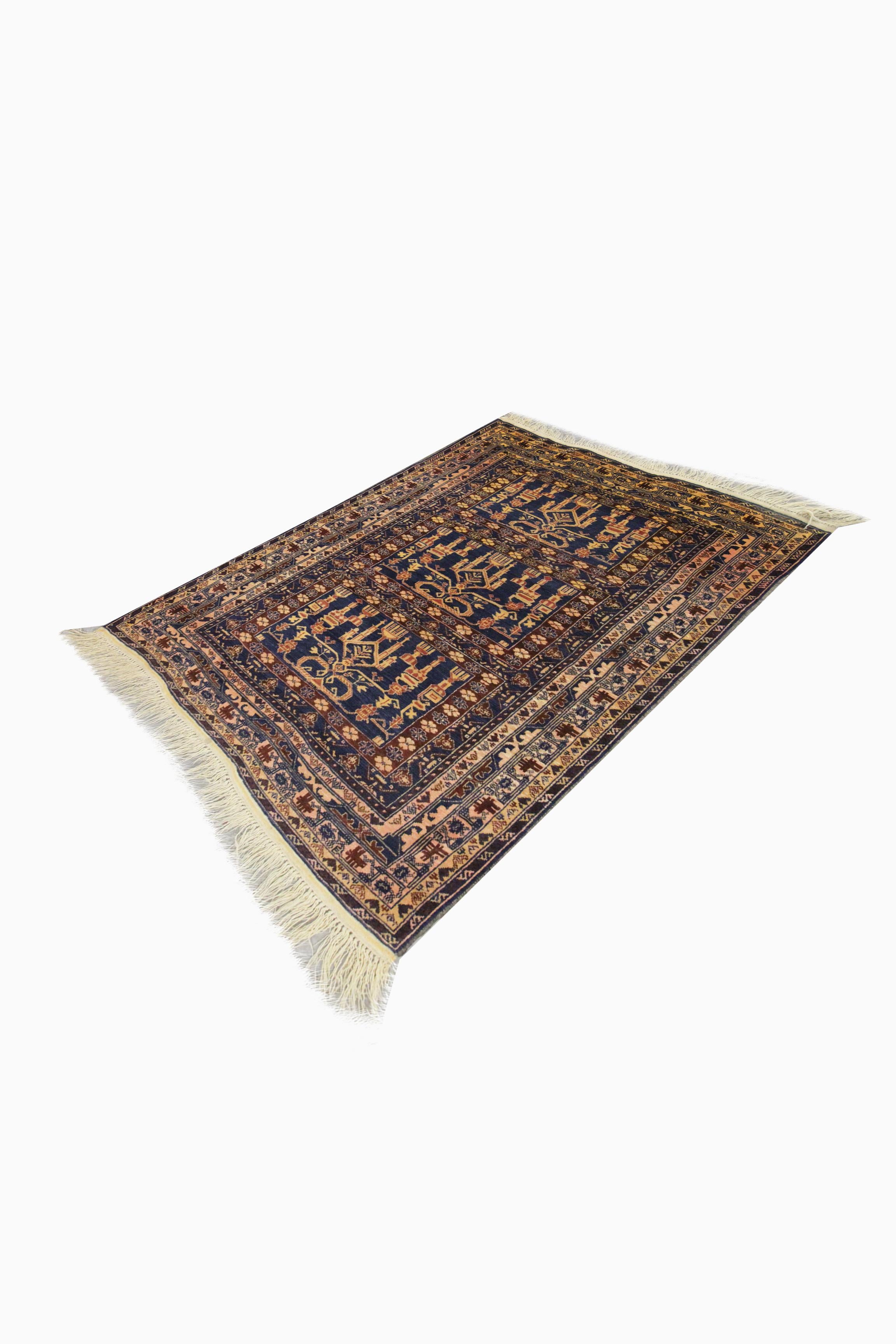 This deep blue wool Baluch area rug is a fine handwoven carpet woven with an intricate traditional design. The central design features a bold symmetrical pattern woven in a trio of rectangular shapes through the centre layered border has been framed