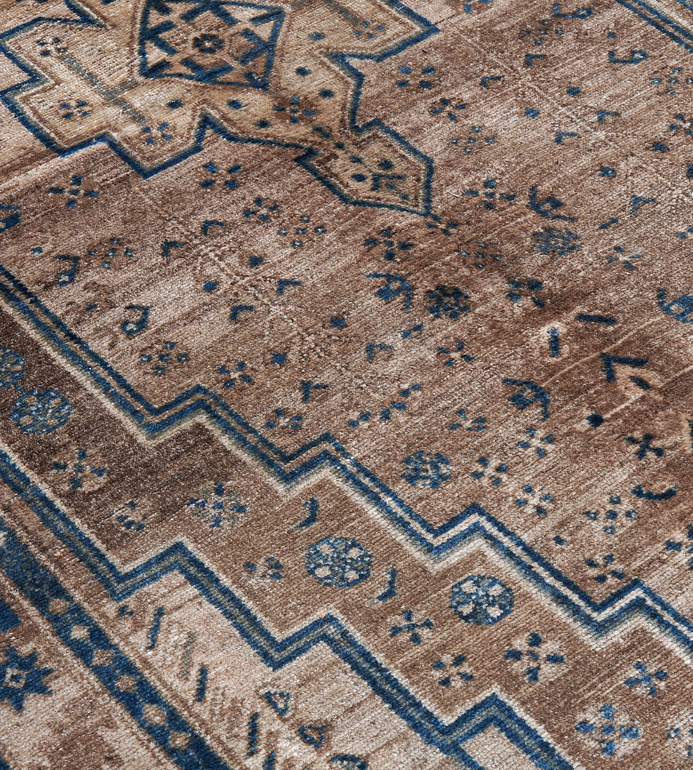 This traditional hand-woven Persian Bidjar rug has a shaded medium brown field with geometric rosette motif enclosing concentric stepped lozenges and central gometric lozenge medallion, with similar tan spandrels, in a shaded beige floral geometric