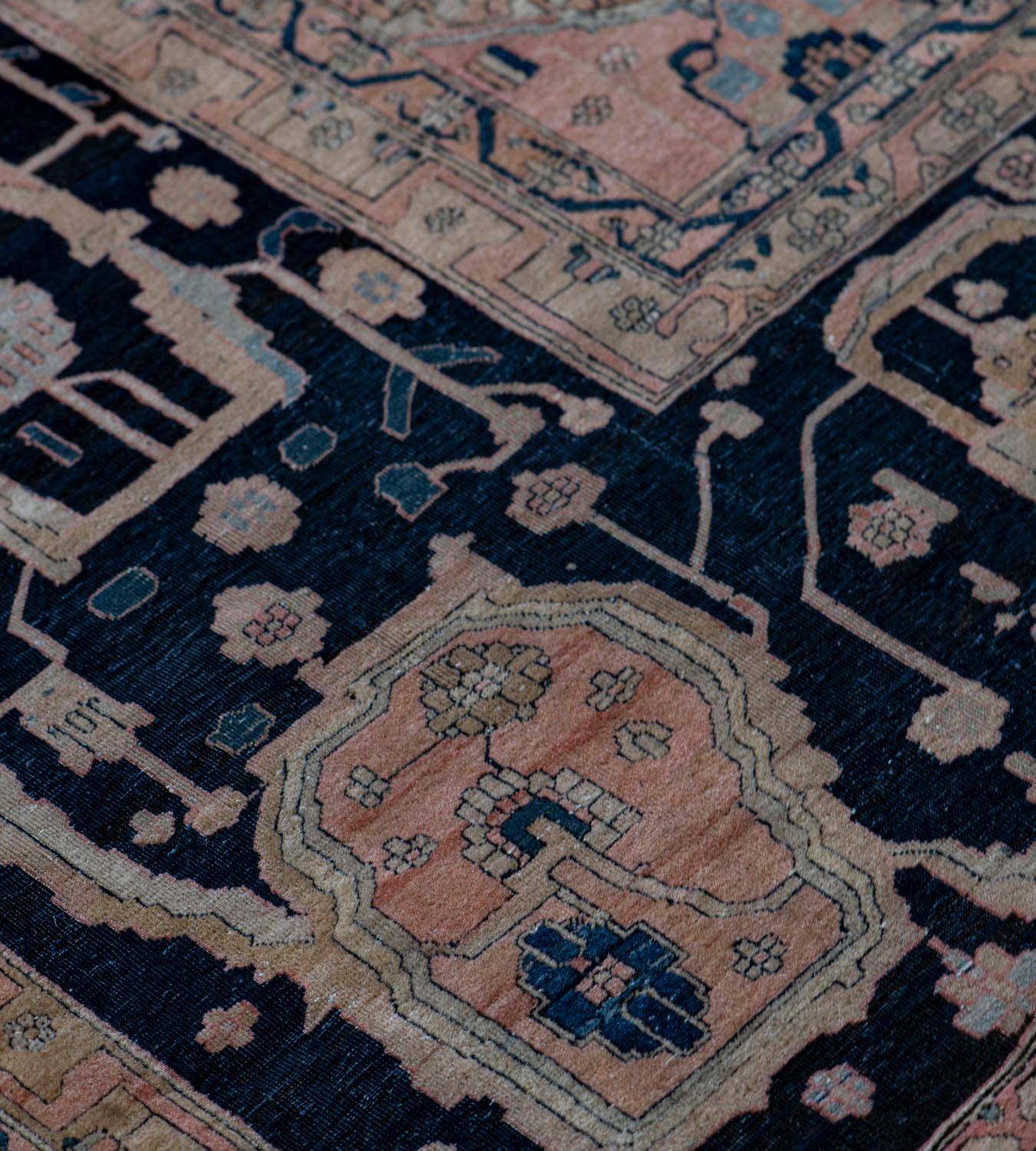 This traditional handwoven Persian Kashan Mohtasham rug has a dusty pink field with horizontal rows of ivory cartouches containing dense floral vine linked by an ivory and charcoal-black rosette, the cartouches divided by indigo columns containing
