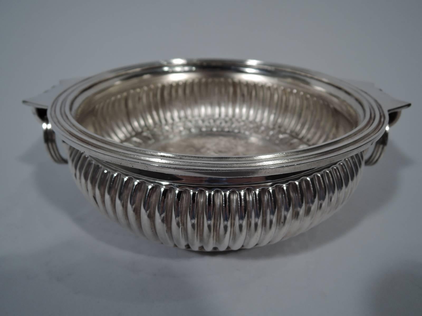 Traditional sterling silver bowl. Made by Miss India in Jaipur, India. Bellied with reeded rim, gadrooning, and small inset foot ring. Fluted side handles with jangly loose-mounted rings. Bottom exterior decorated with central flower surrounded by