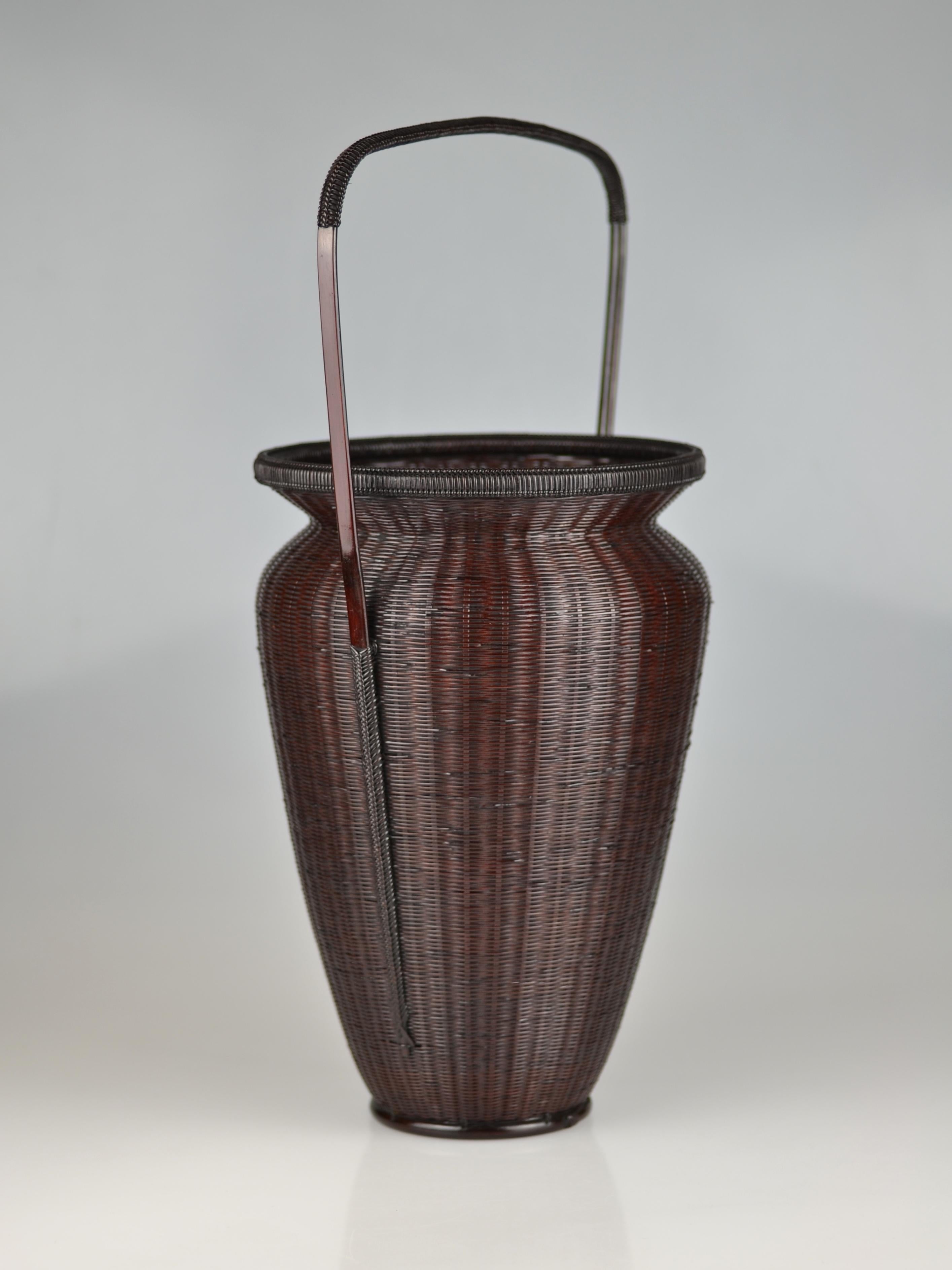 Traditional, well-balanced bamboo flower basket in Chinese style with rattan wrapped handle. The mat plaited wall ends in a wide open mouth with a rattan wrapped rim. The handle is beautifully woven into the vessel's side and finishs close to the
