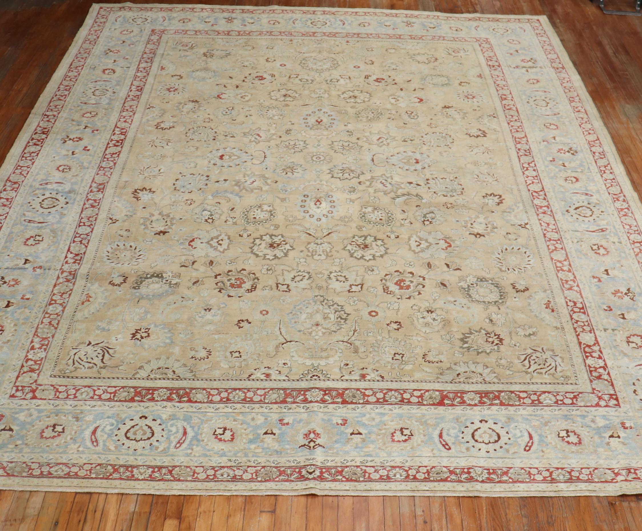 An oversize Persian Meshed rug with an all-over formal design on a khaki field, an icy blue border, accent colors in red and brown, circa 1920.

Measures: 12'2'' x 16'8''

The city of Meshed is one of Iran's oldest cities, located in the
