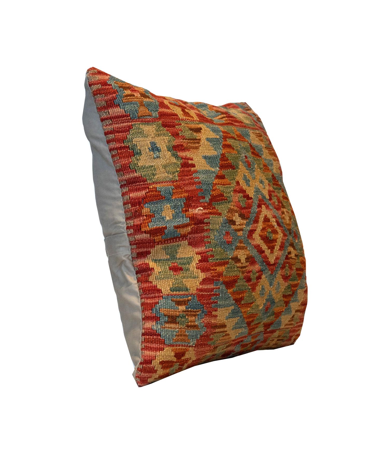 This fantastic cushion has been woven by hand using traditional kilim weaving techniques with hand-spun wool. Featuring a symmetrical geometric pattern woven in beautiful rustic colours. Including an olive green, rust orange, red and blue. These