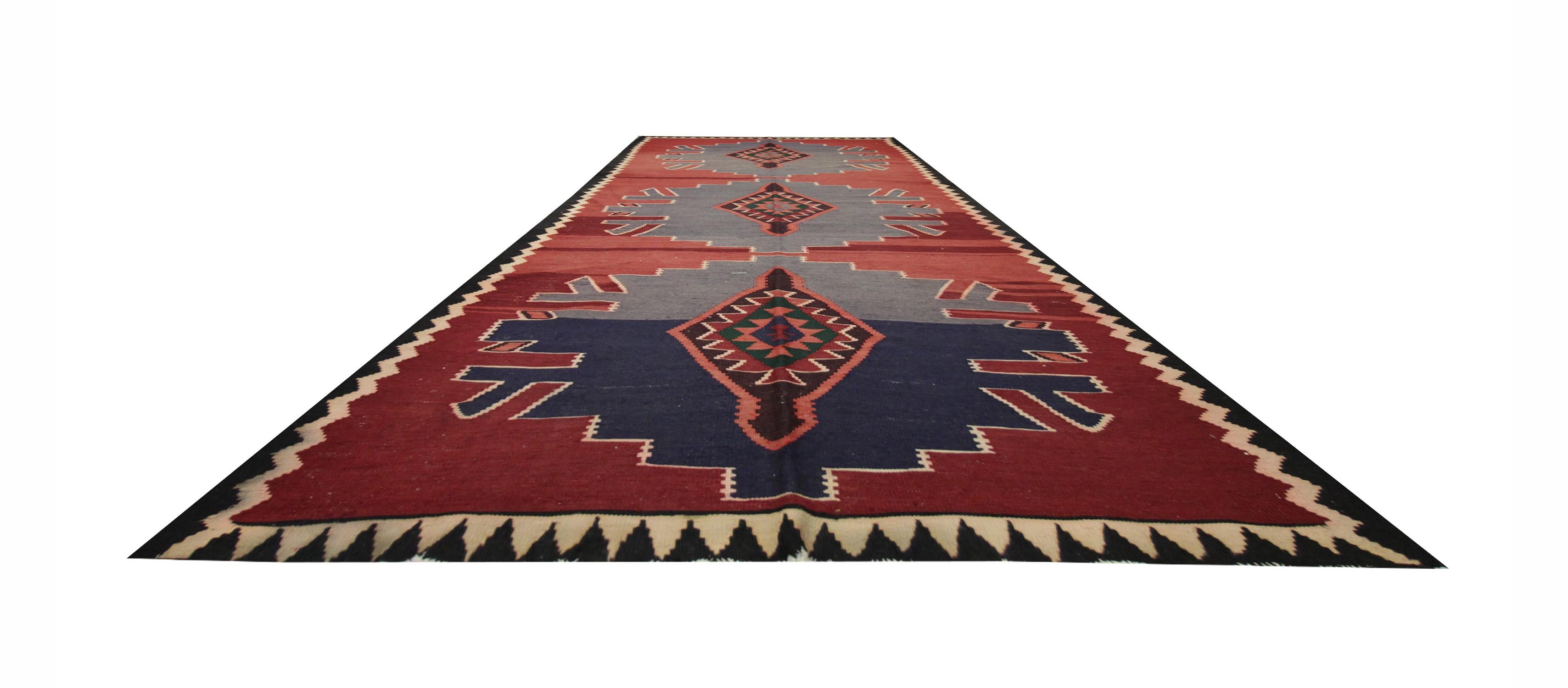 This fine wool area rug was woven by hand in the 1960s/70s with a tribal design. Woven on a rich red background with three large medallions in accents of deep blue and brown. The bold geometric design and simple colour palette make this piece the