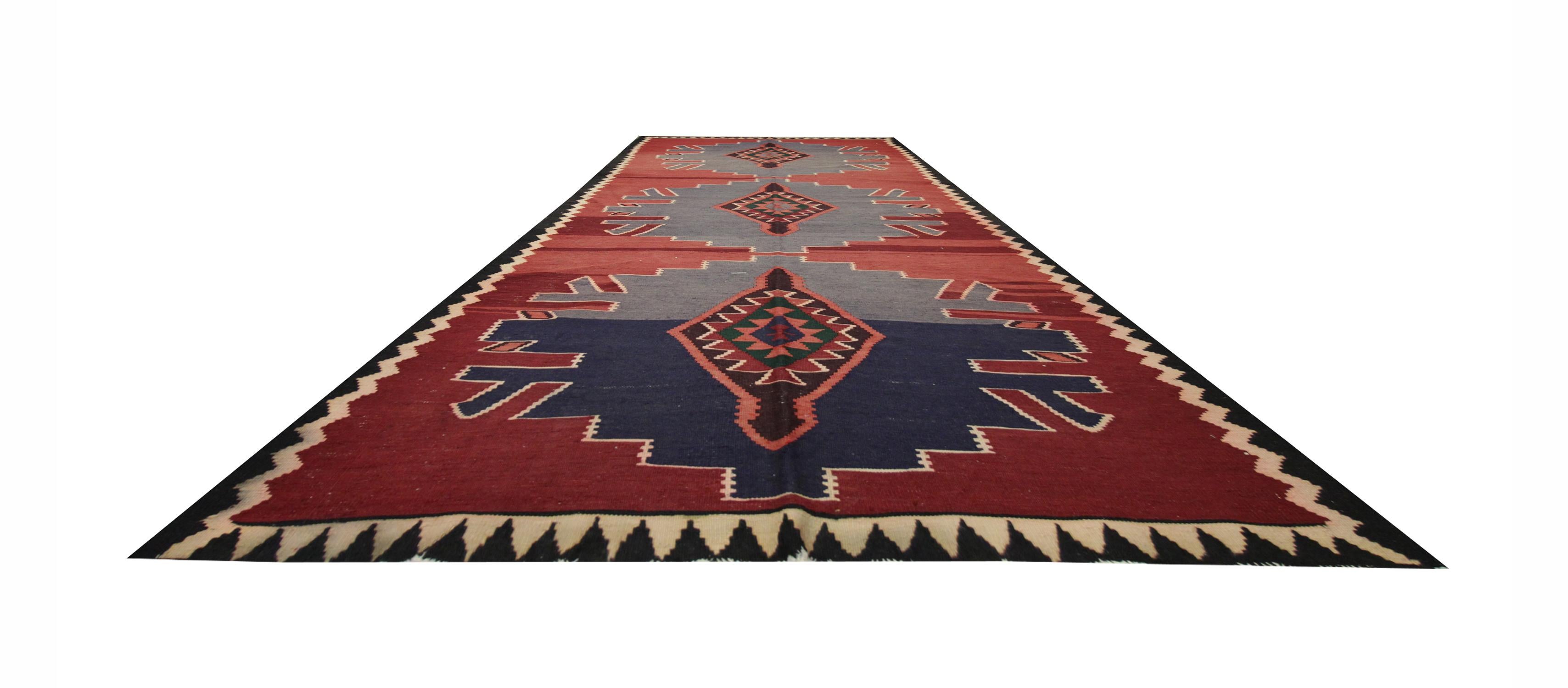 Questo tappeto di lana pregiata è stato tessuto a mano negli anni '60/'70 con un disegno tribale. Tessuto su un ricco sfondo rosso con tre grandi medaglioni con accenti di blu e marrone. L'audace design geometrico e la semplice palette di colori