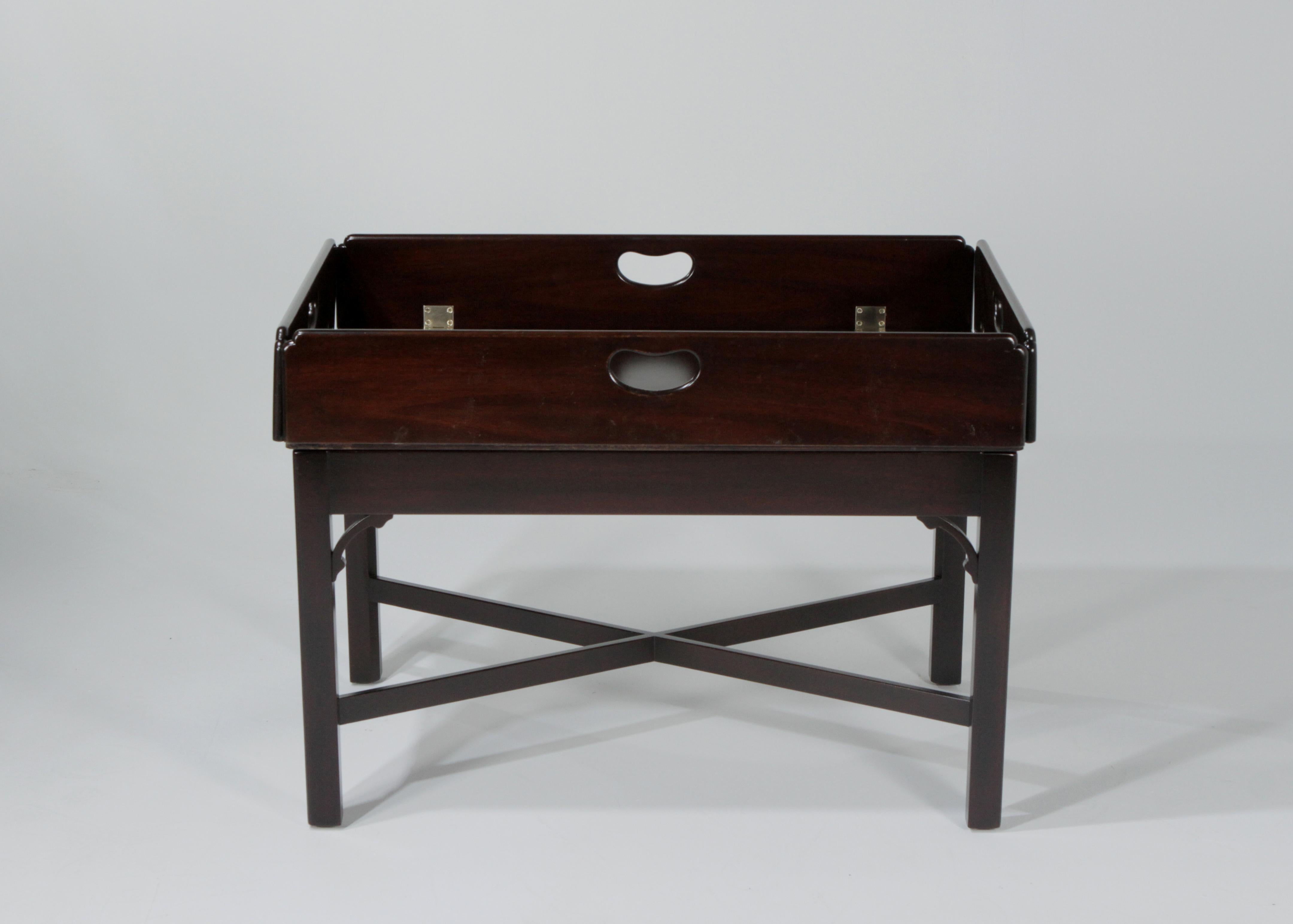 A very nice Kittinger mahogany drop-leaf butler tray table. This table is made of solid mahogany with a mahogany veneered top with quartered mahogany banding, pierced headholes, corner brackets and crossed stretchers. With the drop up the table is
