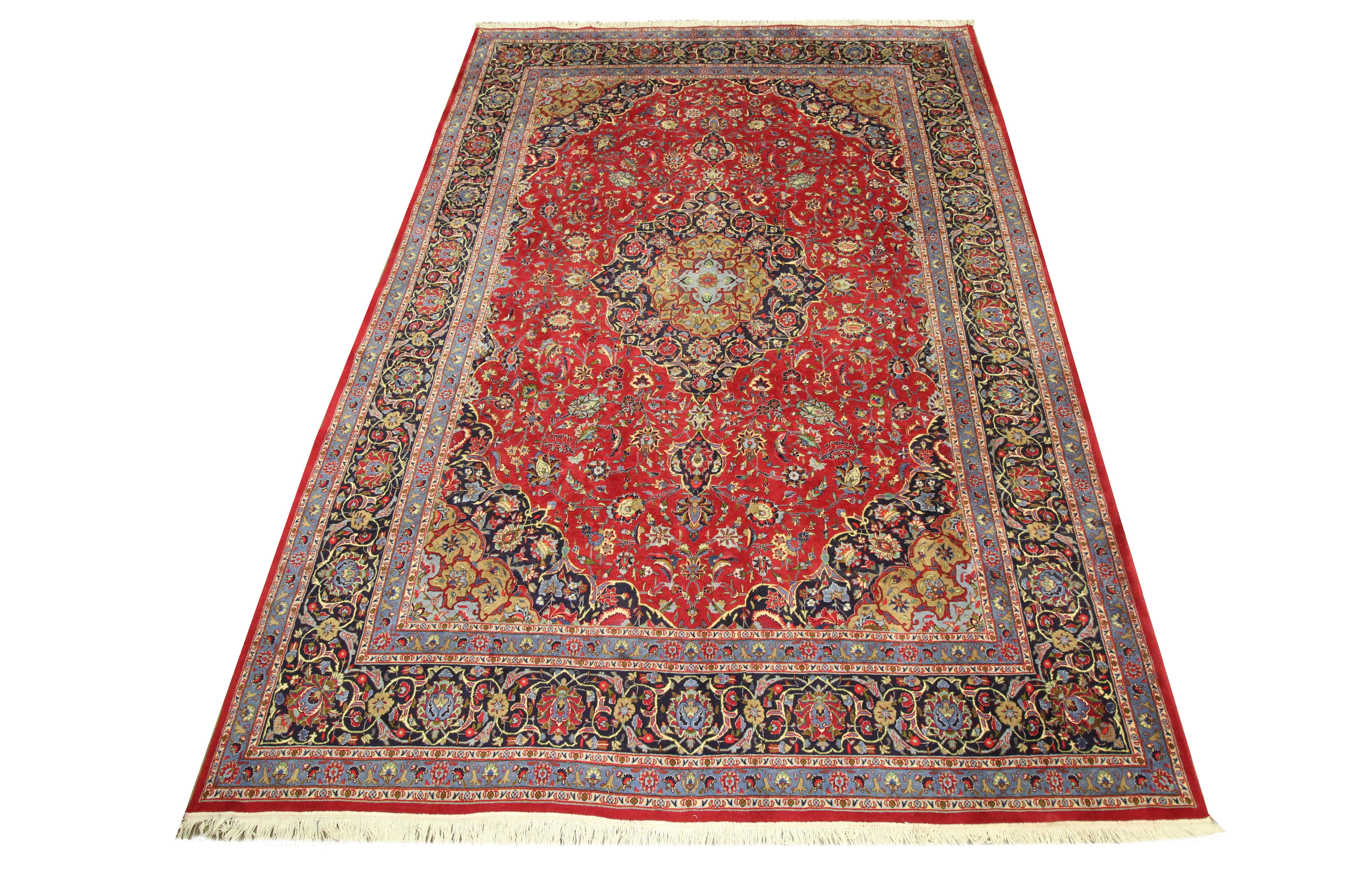 This beautifully handwoven oriental area rug is a traditional carpet woven in the mid 20th century, circa 1950. The central design has been woven on a rich red background and features an intricate medallion design that has been framed with a