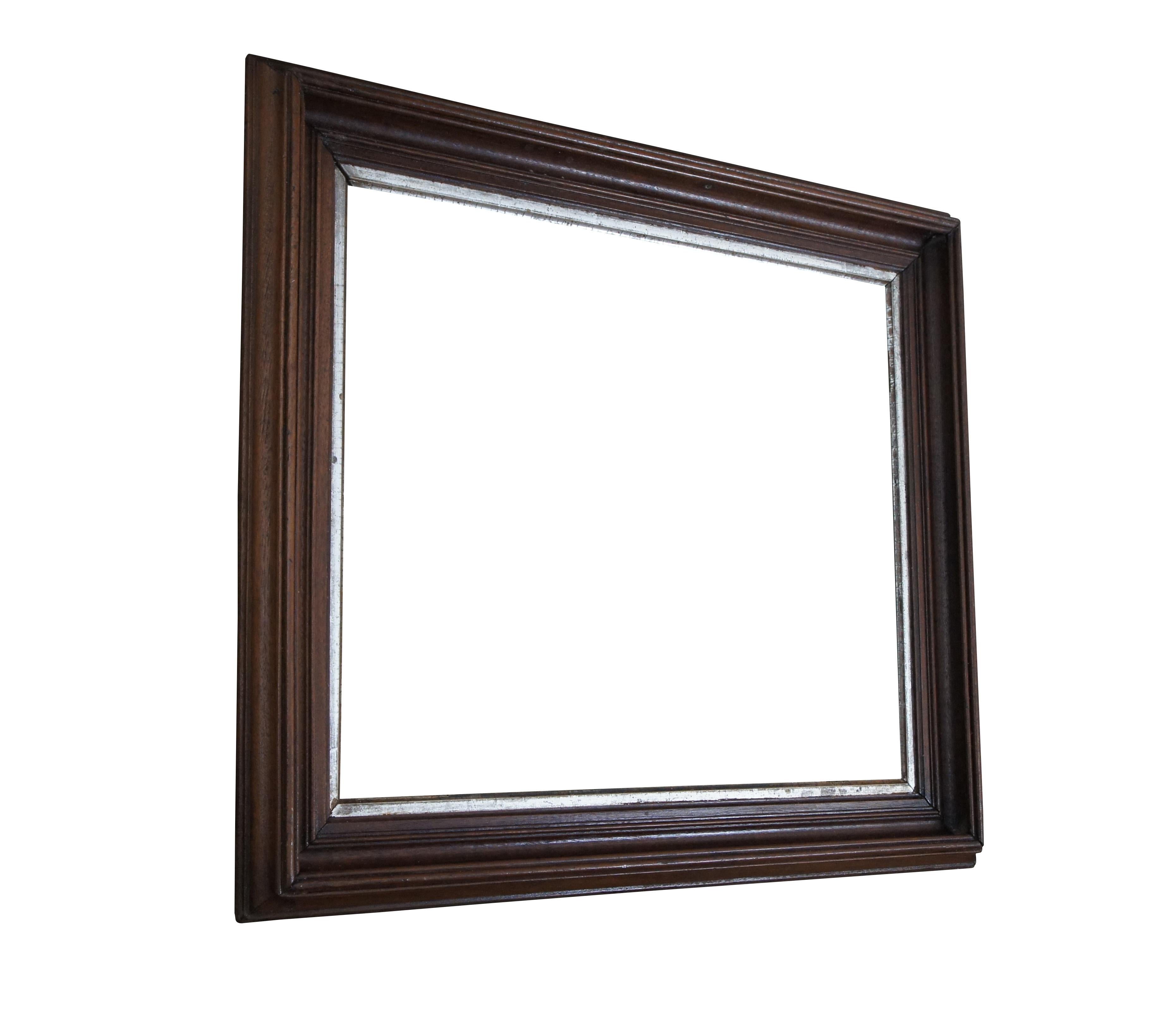 Rectangular wooden mirror / picture frame with carved bevel and silver gilt trim along the inner edge. Made from mahogany.

Dimensions:
27.5