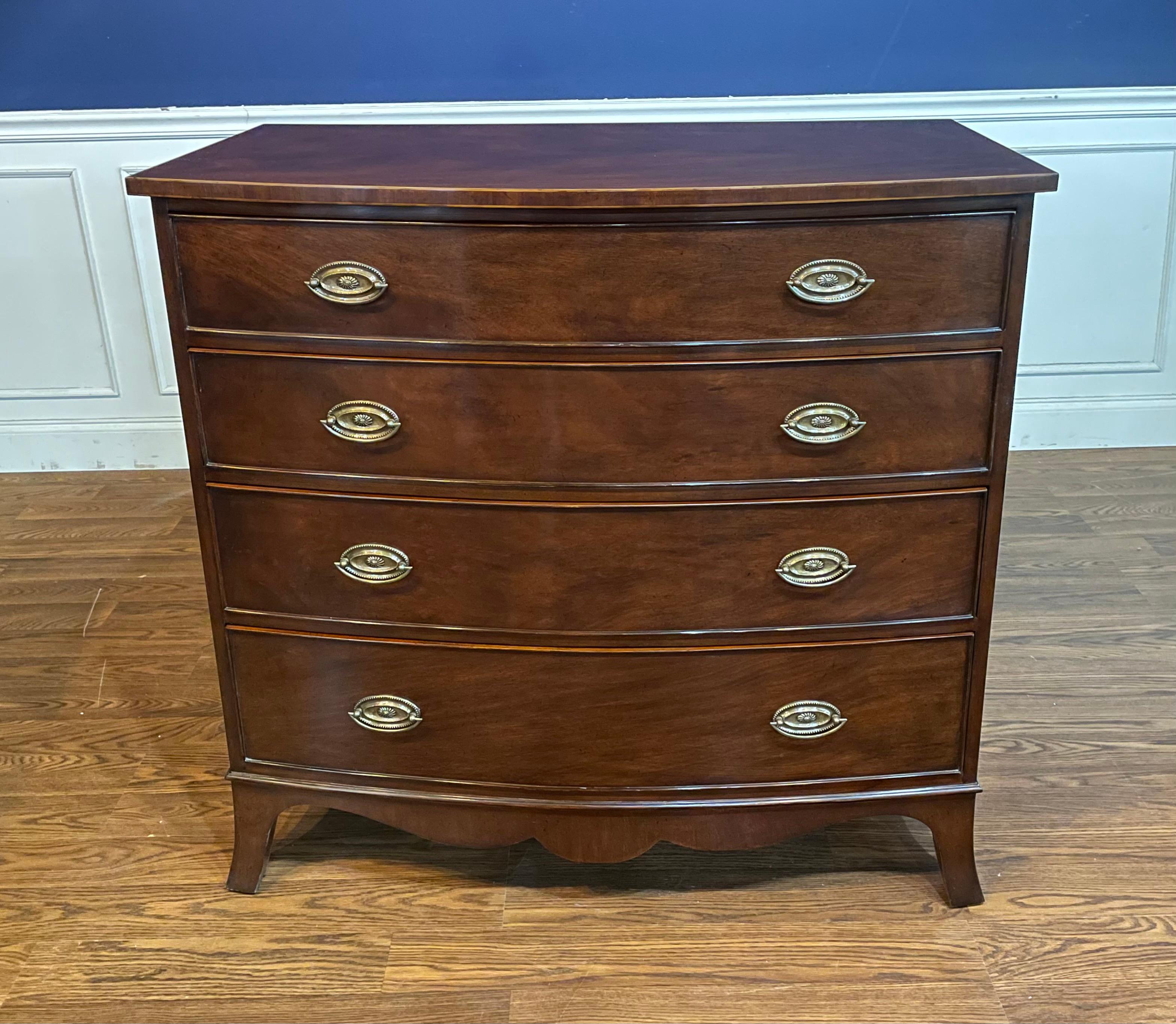This is a classic Mahogany inlaid bow front chest by Leighton Hall. Its design was inspired by chests from the early 1800s. It features four drawers, solid brass hardware and faux key holes. The drawers are dovetailed and oak lined.  It has a hand