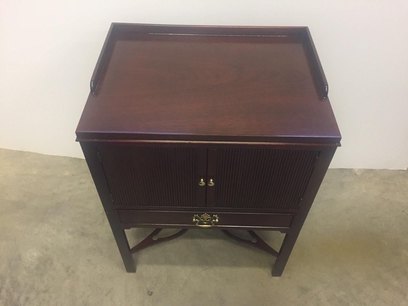 A traditional mahogany cabinet end table or nightstand having double doors and a single drawer on a classic stand.