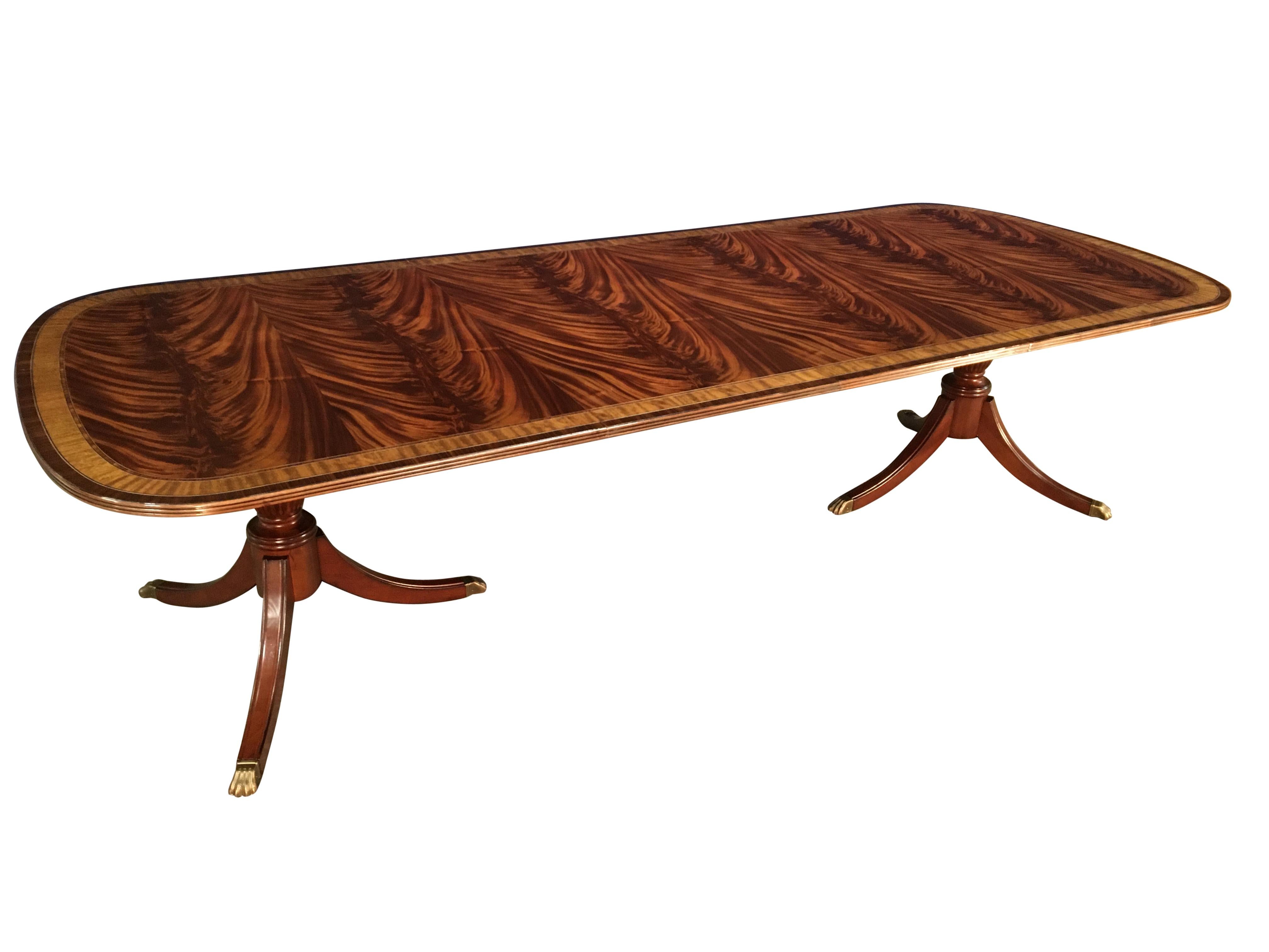 This is a made-to-order large traditional mahogany dining table made in the Leighton Hall shop. It features a field of slip-matched swirly crotch mahogany from West Africa and satinwood and Santos rosewood borders from South America. The borders are