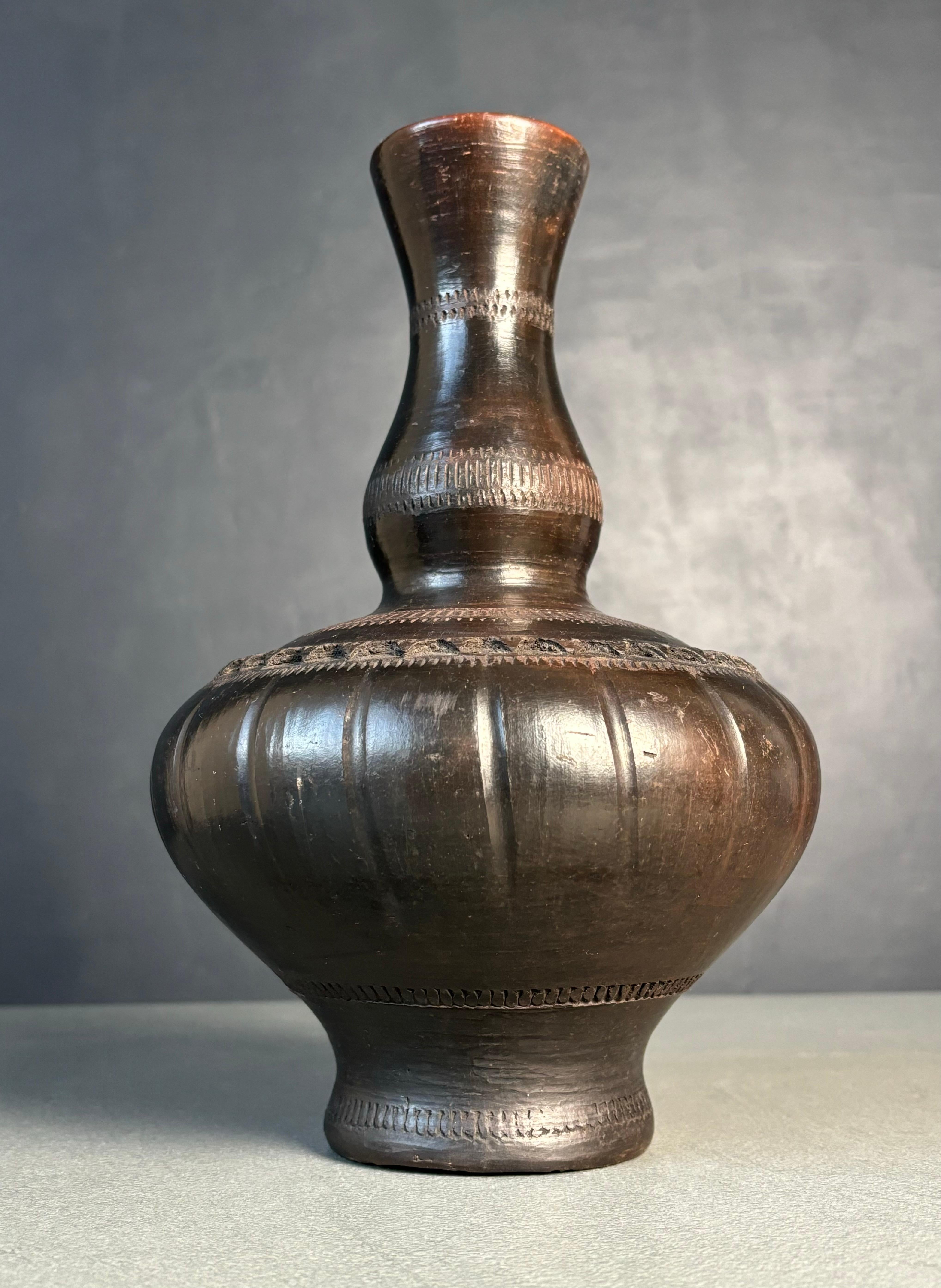 Antique traditional Southeast Asian ceramic Labu Sayong water cooler carafe bottle vase with hand-carved graphic and organic decorations. Dark blackish brown gourd shaped shiny piece handmade with Perak river bank clay. Beautiful vintage condition.