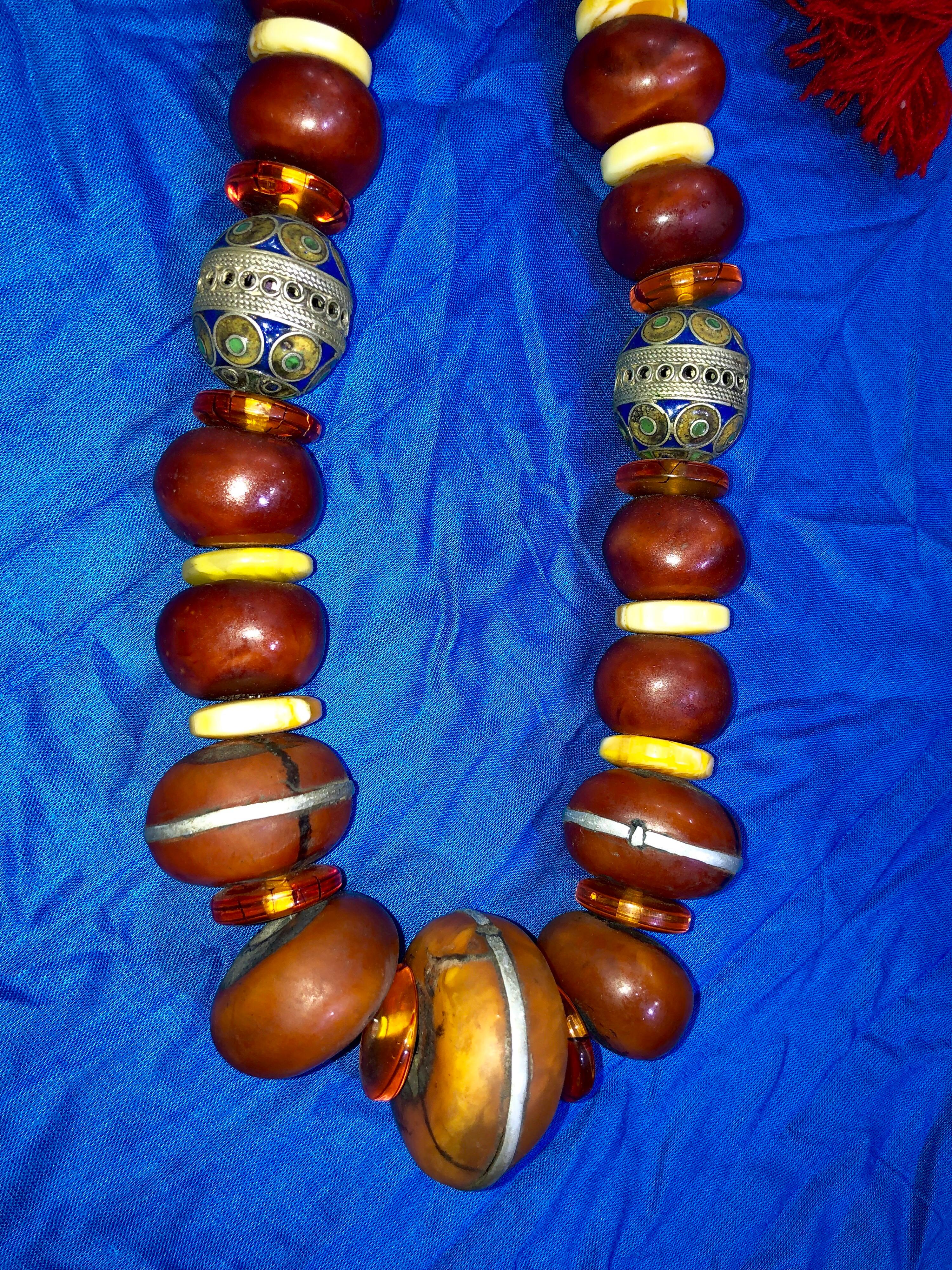 This Berber Wedding and Fertility necklace was crafted for a Moroccan Bride to wear on her wedding day. It features two enameled Tagemout fertility beads and a mix of Amber resin beads. In addition there are Amazonite beads and shells.

Tagemout