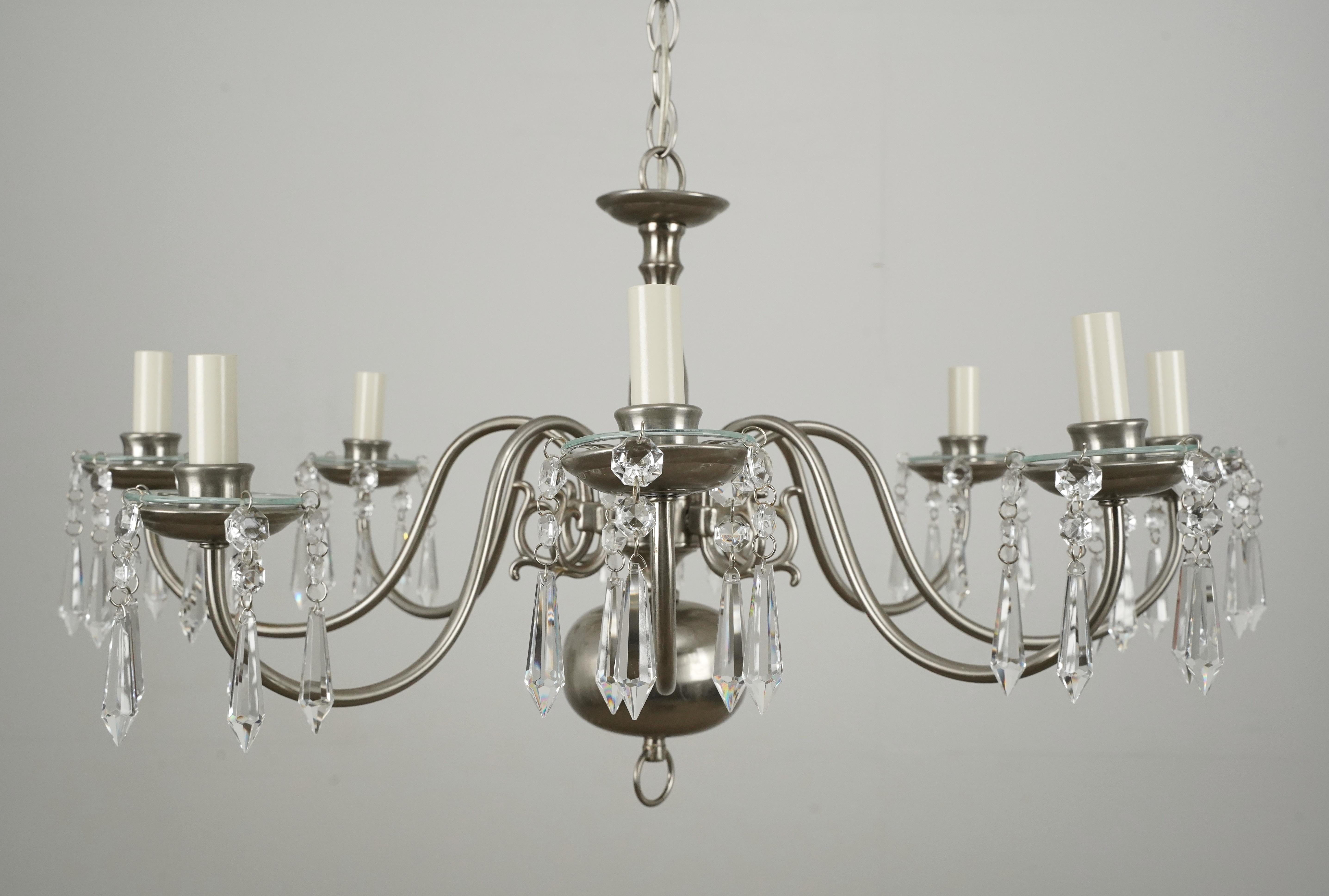 Araña de cristal de 8 brazos de estilo tradicional fabricada en latón acabado niquelado y cristales octogonales y en forma de lanza. La cadena es de acero niquelado. Esta luz requiere ocho bombillas candelabro E-12. Limpiado y restaurado. Buen
