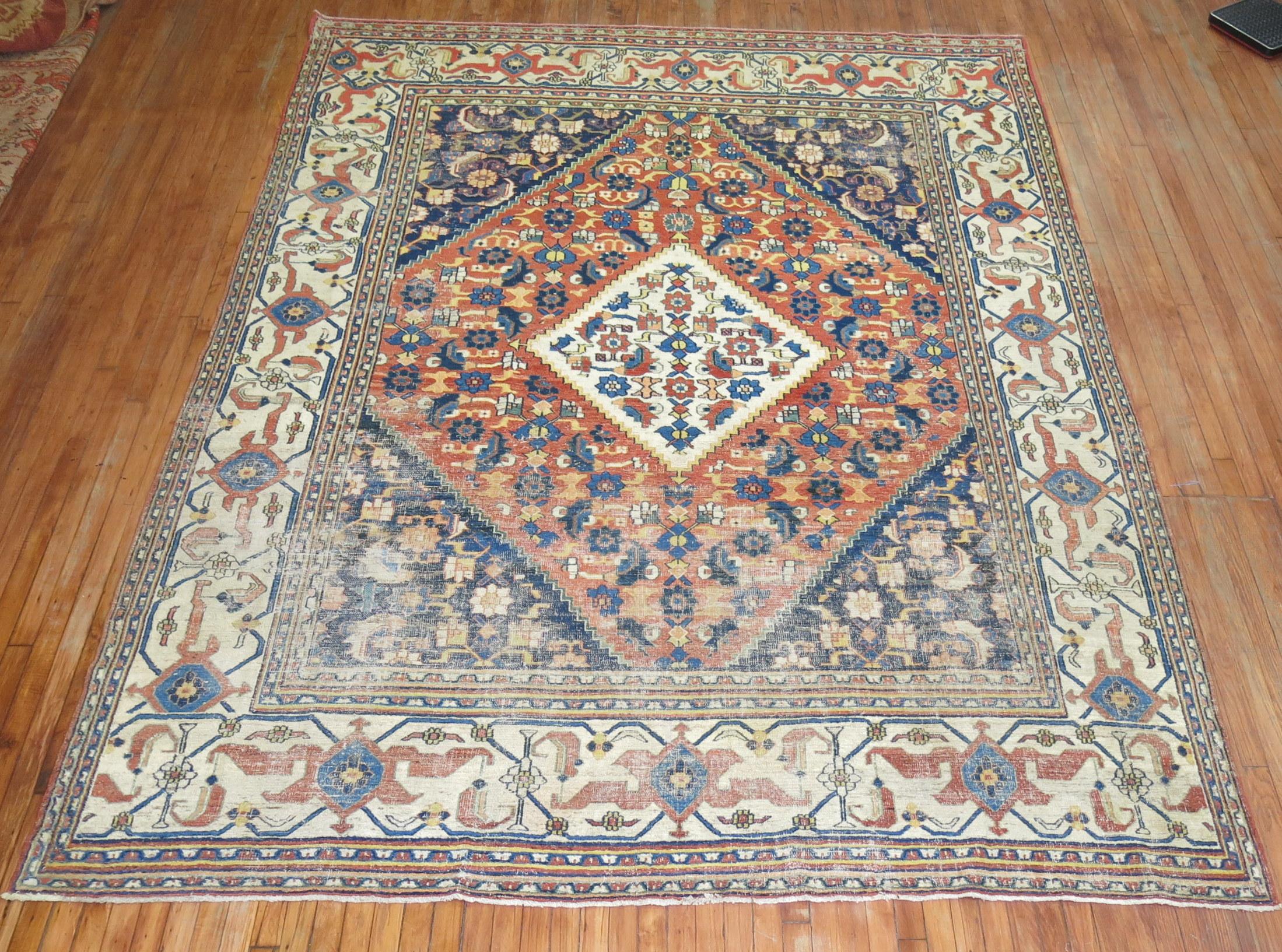 A naturally worn Persian doroksh rug with a traditional pallete in navy orange and ivory colors from the early 20th century,

circa 1910, measures: 8'6