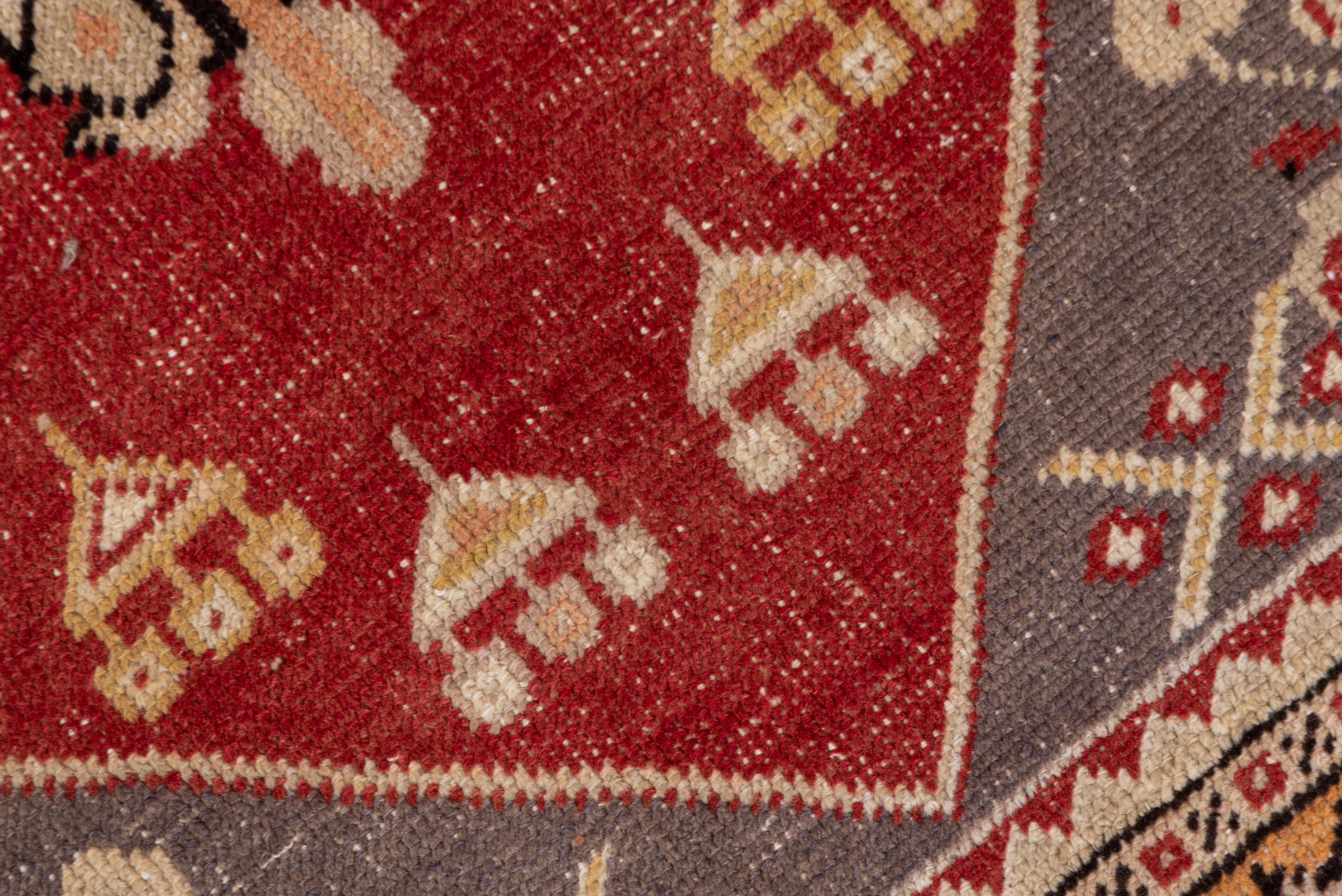 The red field displays a large cream palmette pendant medallion with dark brown, red and orange-brown accents, with triangular jewels suspended at both fields ends. There are green spandrels and a mustard main border with a star pattern.