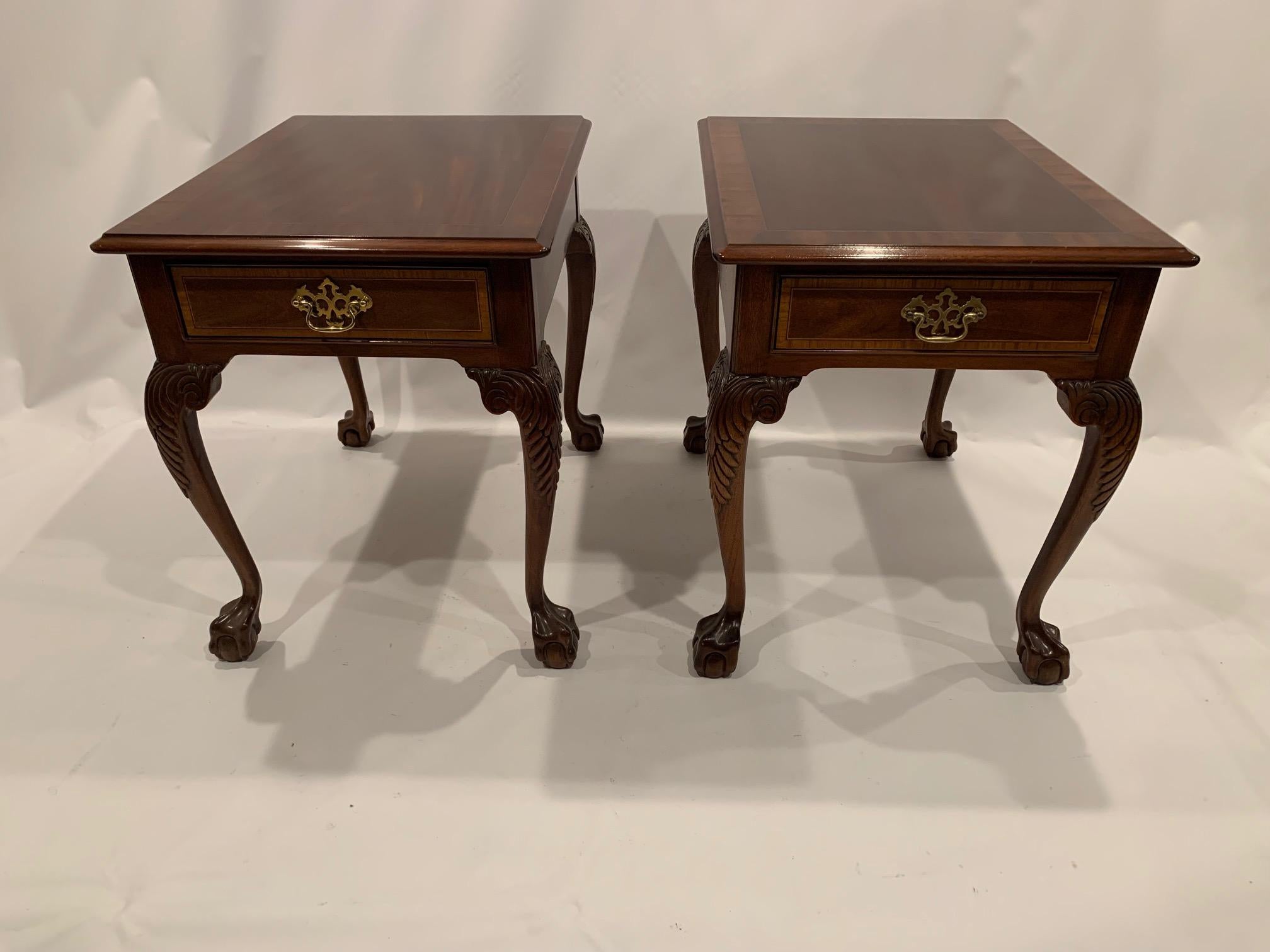 Handsome traditional Chippendale style rich mahogany end tables or night stands having ball and claw legs, single drawers, and brass hardware.