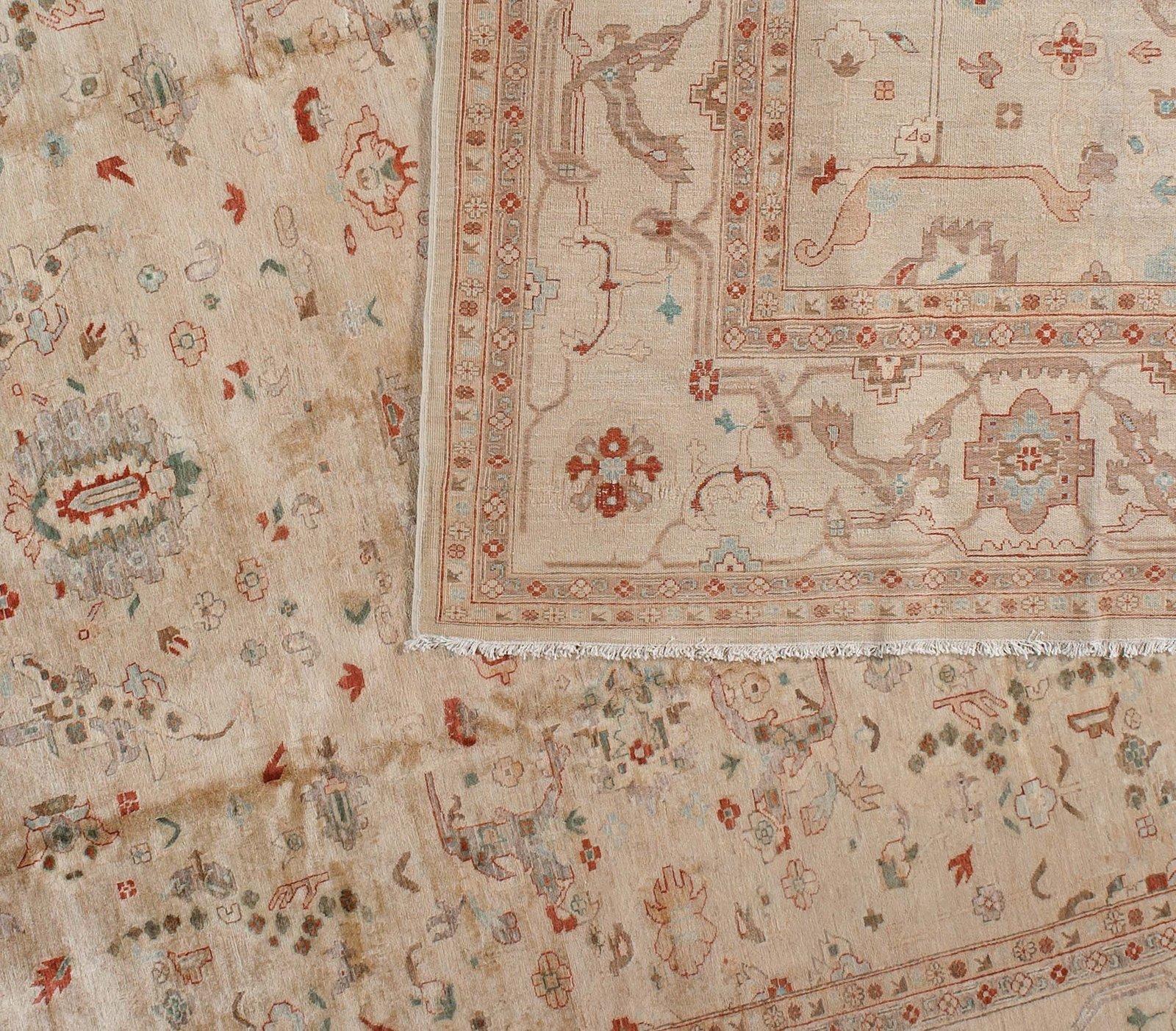 Thin red and green ribbons establish the slightly elongated proportions of this tradition Pakistani wool area rug. A delicate floral pattern in light green, red, coral and taupe adds a charming overlay to the warm and neutral tones of a beige