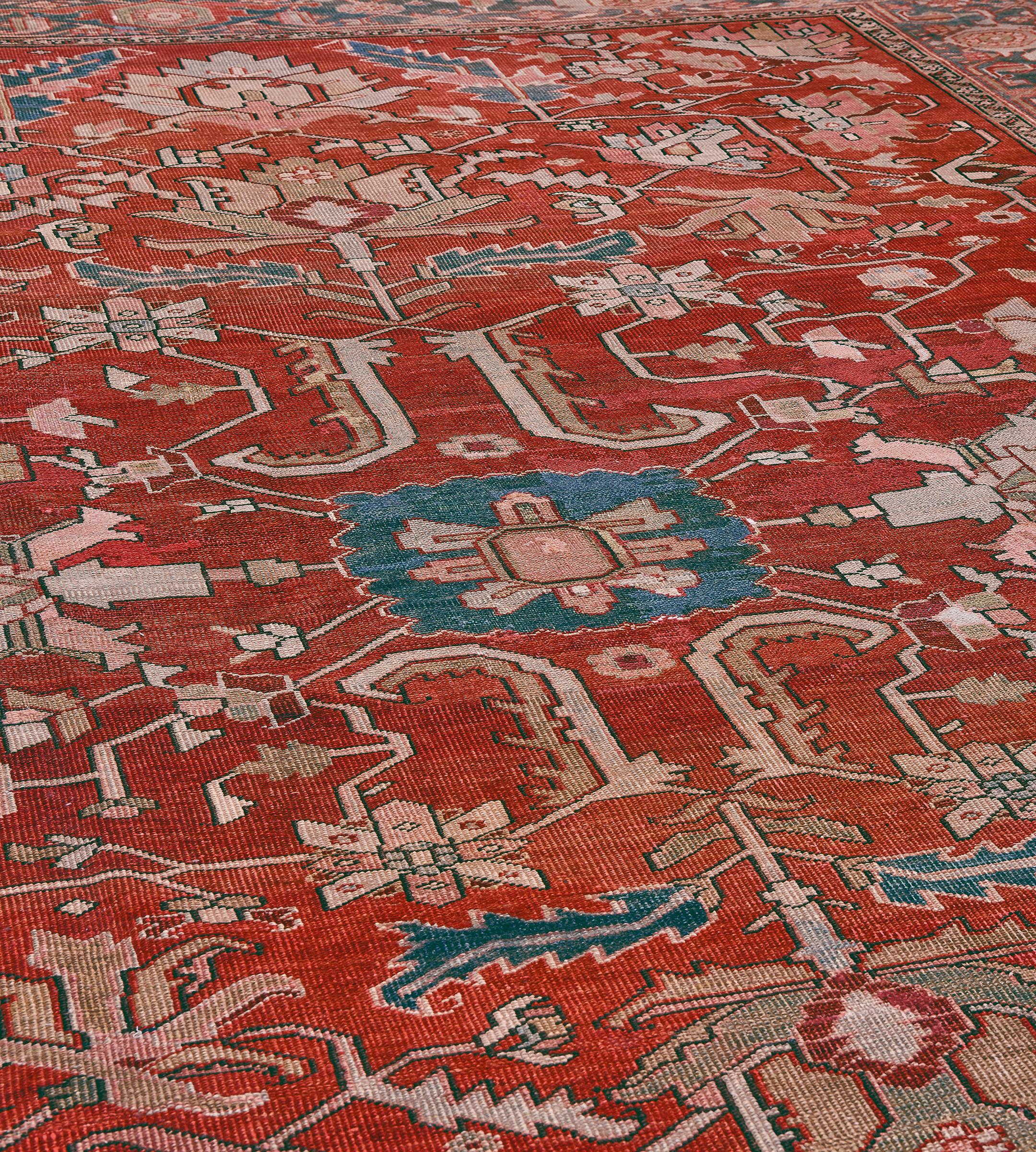 Dieser traditionelle, handgewebte persische Serapi-Teppich hat ein schattiertes, rubinrotes Feld mit breiten Palmetten, die insgesamt eine schräge, florale Rankenformation bilden, in einer schattierten, mittelblauen, mit Schildkrötenpalmetten
