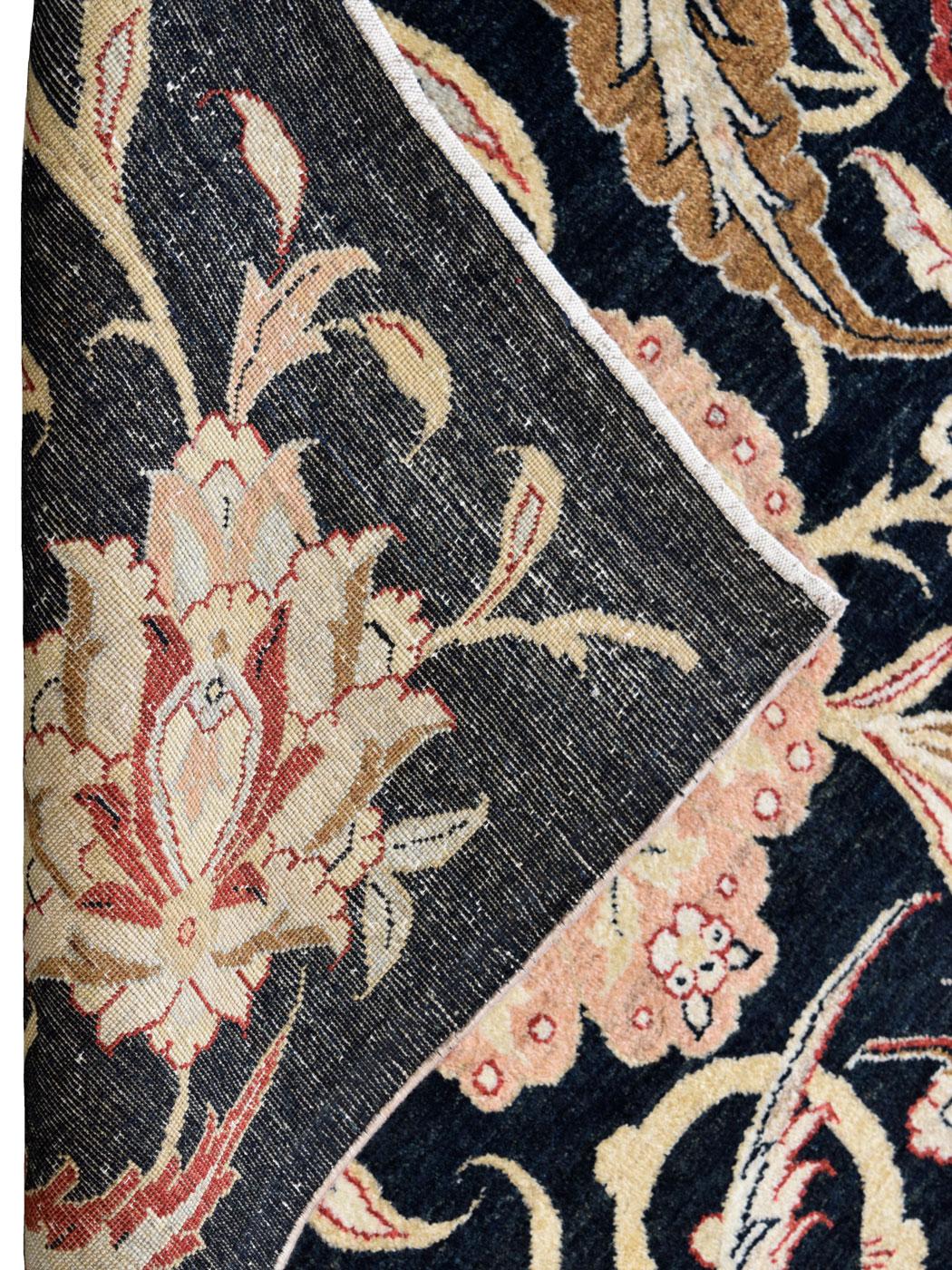 Questo tradizionale tappeto persiano nero, crema, rosso e rosa, che misura 5' x 7', combina un'eleganza senza tempo con un'estetica audace. Il campo nero profondo funge da tela drammatica, amplificando gli intricati motivi floreali oversize resi in