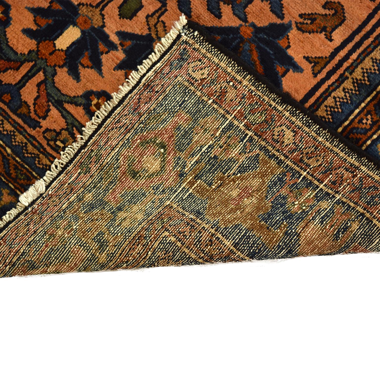 This Antique Lilihan Hamadan wool carpet measures 3’3” x 6’5” and is hand knotted in warm shades of pink, indigo blue, copper orange, forest green, and cream wool. Inspired by a traditional Persian flower garden, the design showcases a central