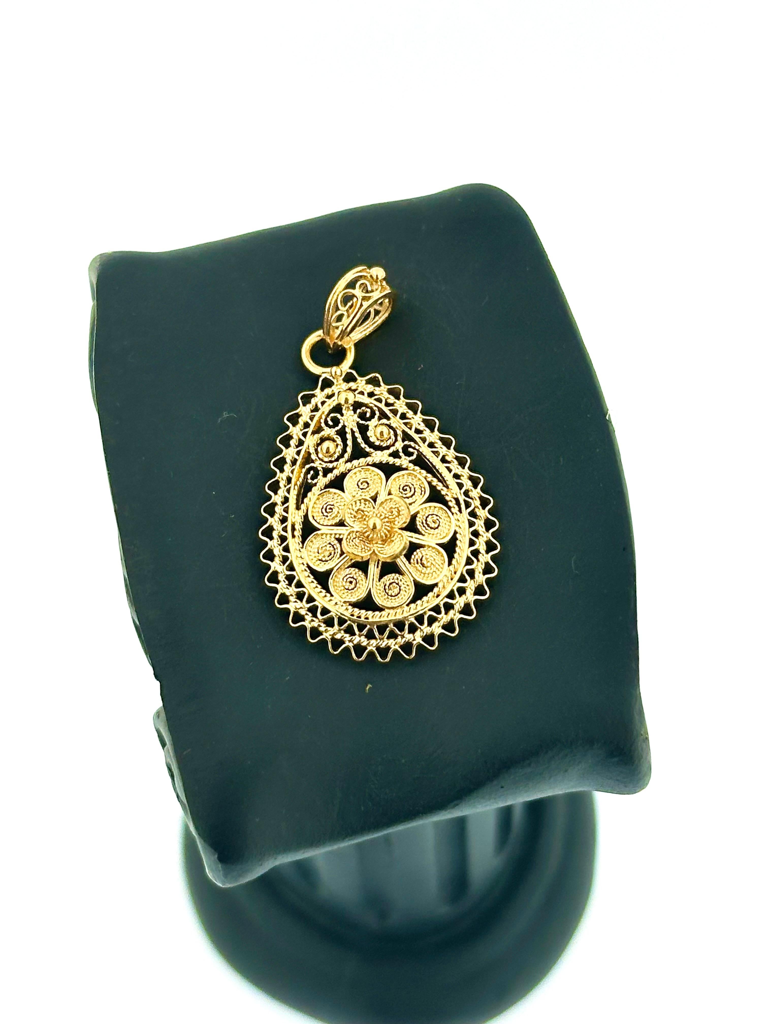 This Traditional Portuguese Drop Pendant is a stunning piece of jewelry, meticulously crafted from 19kt yellow gold and showcasing intricate hand-made filigree. The drop design is a timeless and a classic symbol, while the filigree work highlights