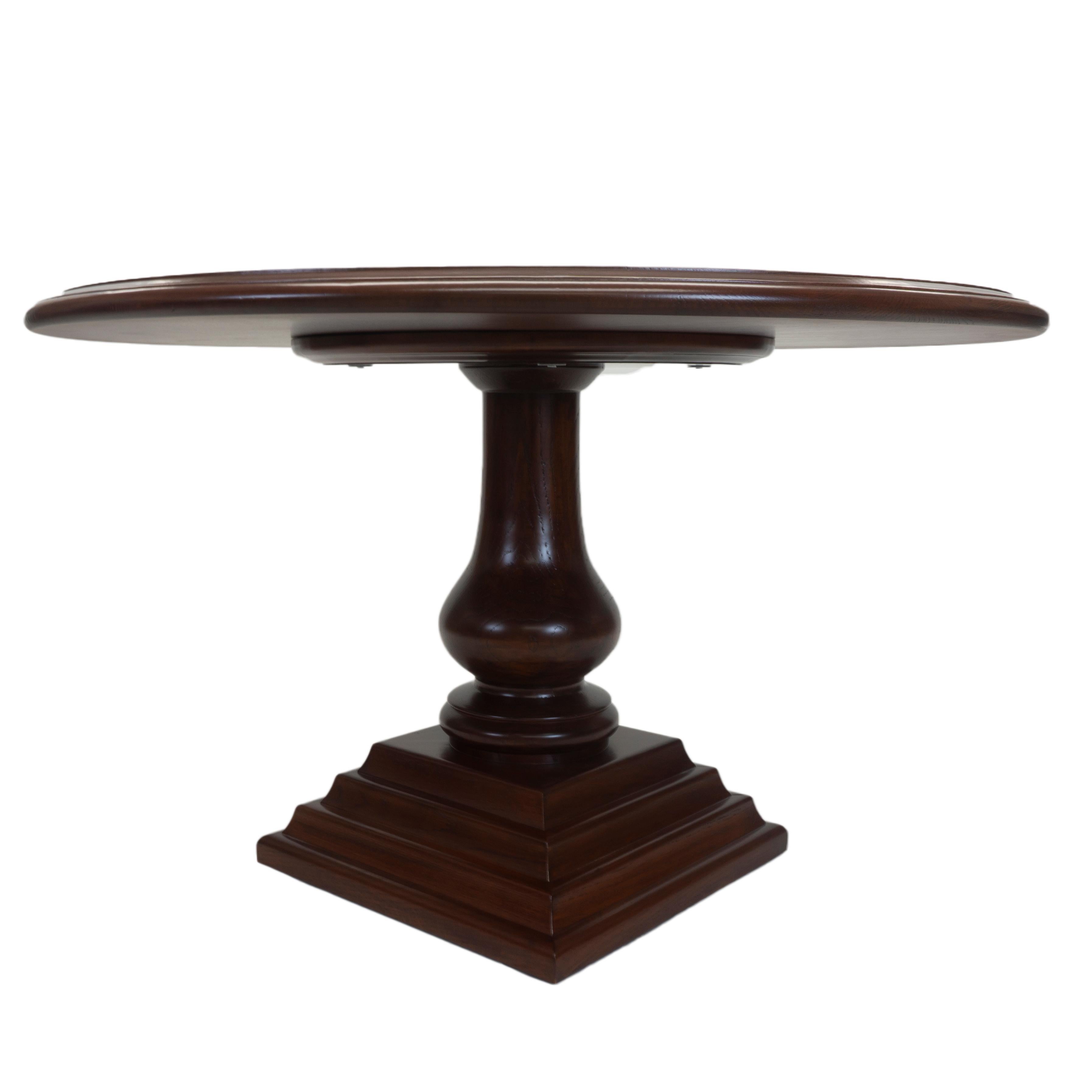 A traditional round dining table. The table features a grooved rim that sits atop a turned pedestal base. Constructed out of sturdy oak and finished in a rich dark walnut. This table is built to order with custom specifications upon request.