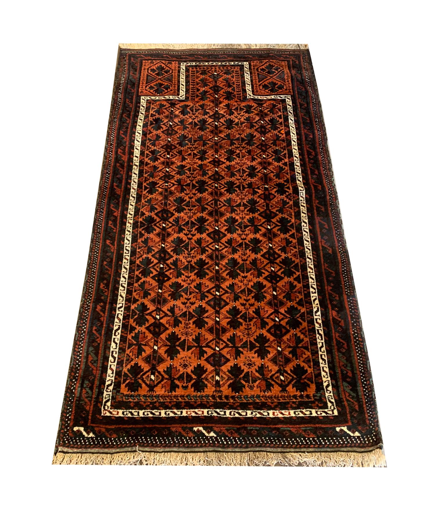 This fine wool rug is an excellent handwoven carpet; this antique piece was constructed in 1920 with locally sourced organic materials. The central design features a rich orange background with brown, black and blue accents that make up the repeat