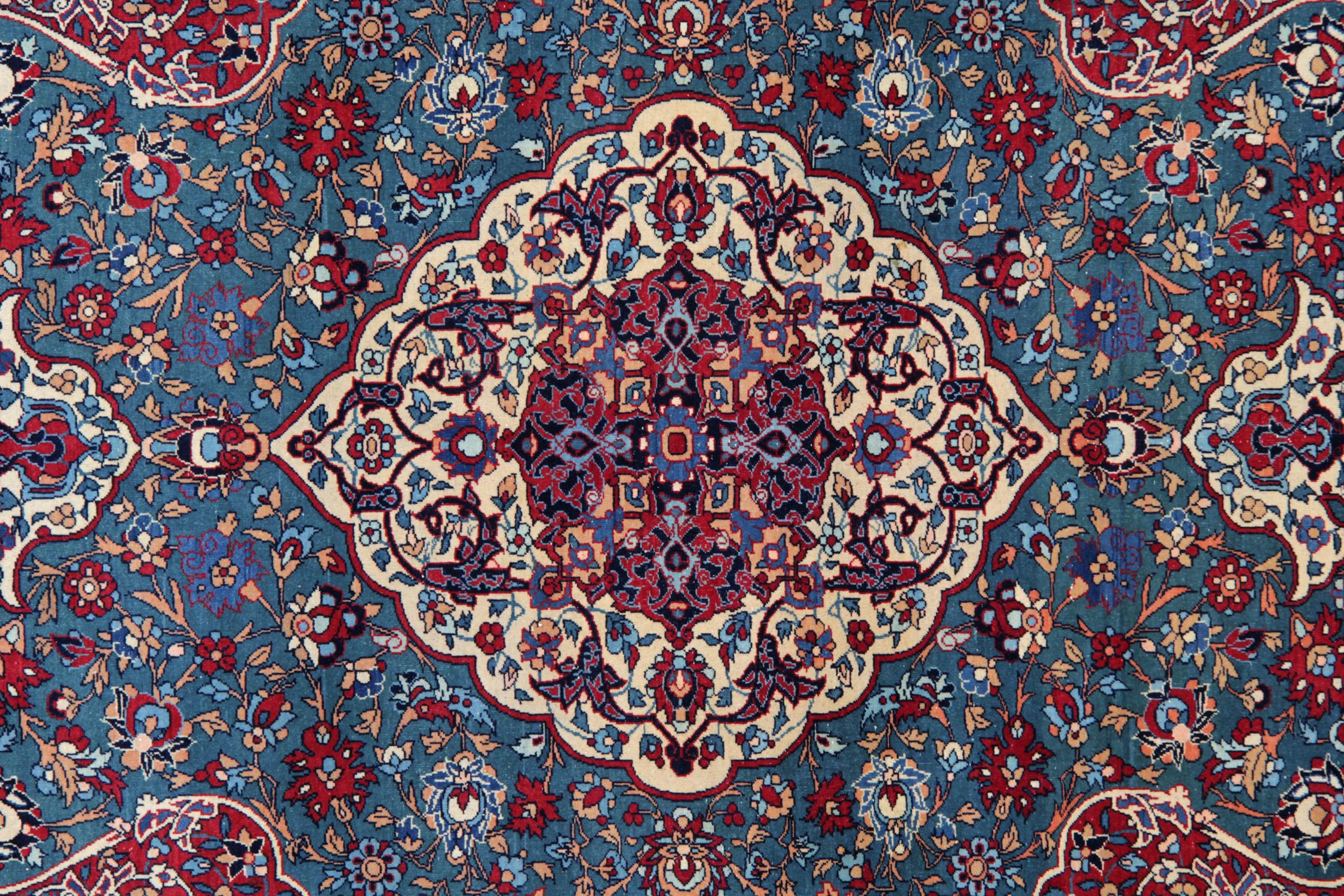 This rare wool rug is a fine example of an antique wool Rug woven by hand in the 1880s. Featuring a traditional intricate central medallion woven on a cream field that floats on a teal blue background with floral motifs and scrolls running through