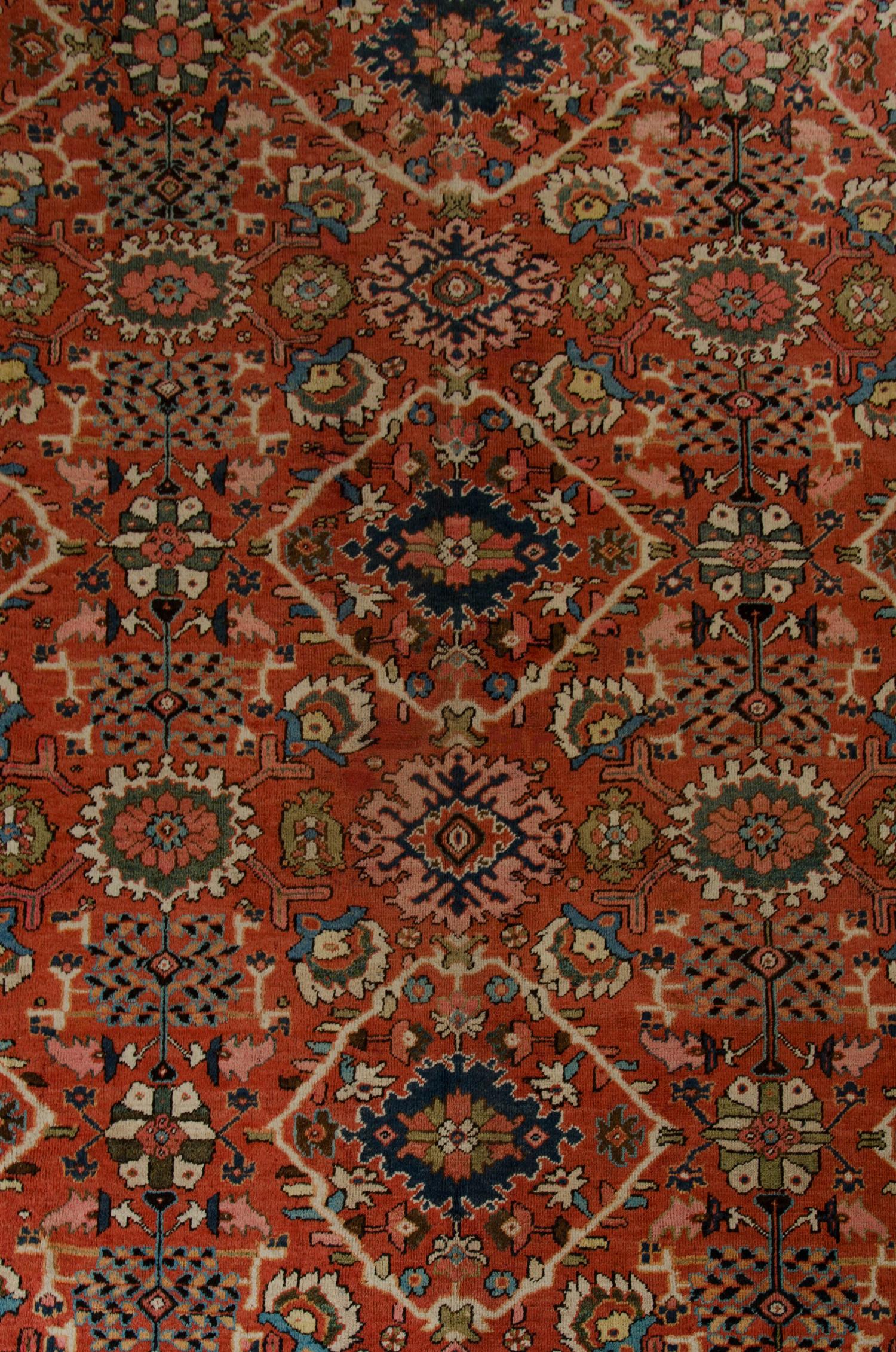 This antique rug was handwoven with muted red-orange and beige tones. With accent colours of blue and green. The design features a symmetrical motif pattern through the centre. A highly detailed repeat pattern border encloses this. Suitable for both