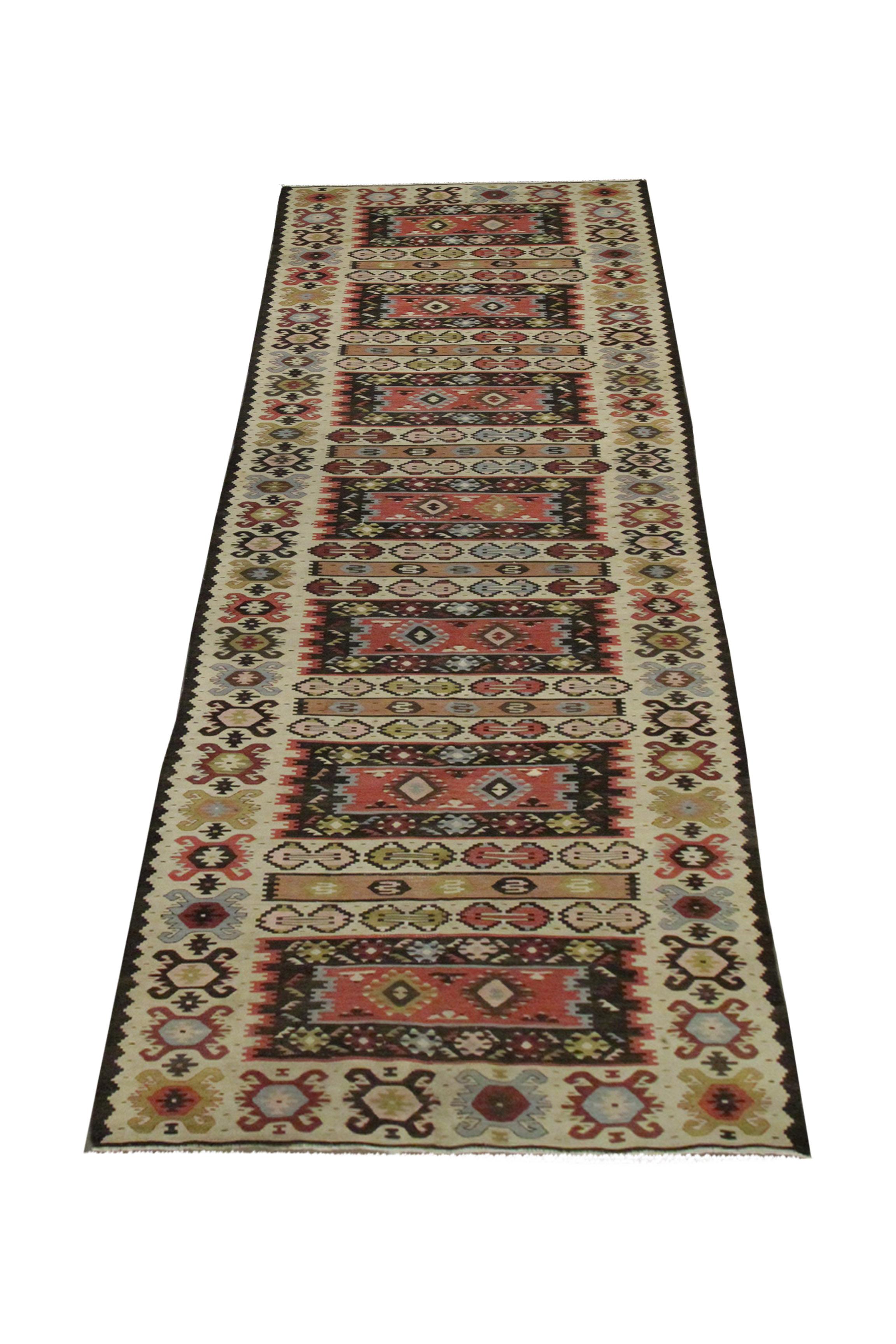 This area rug is a handwoven kilim runner from Sarkoy, Turkey, woven by hand in the 1940s. The design has been woven on a cream background with brown, red, mustard and rust accents that make up the geometric stripe design. The rustic colour palette