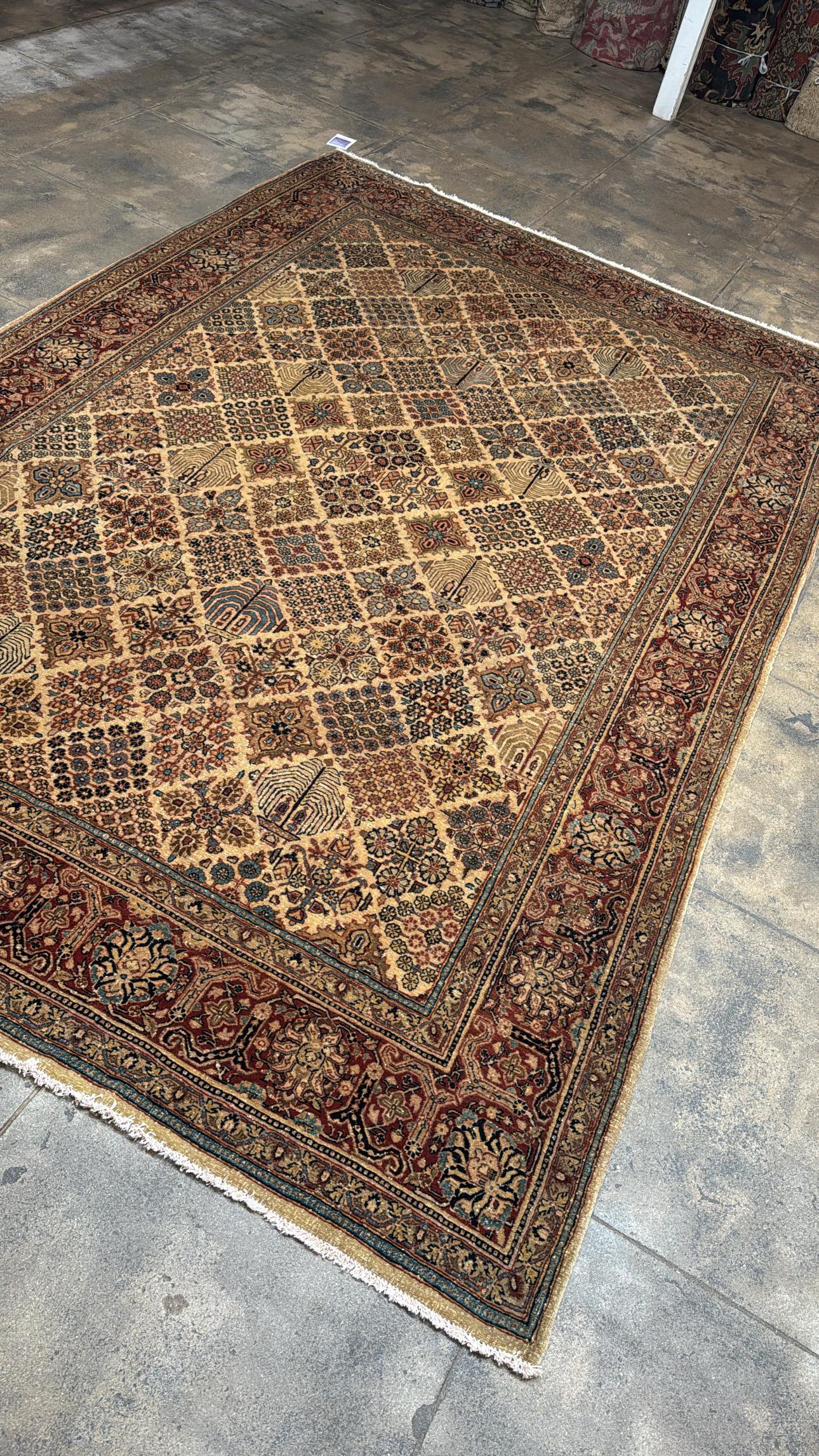 Ce tapis de style sarouk en laine nouée à la main présente un motif de panneau de jardin rare et visuellement complexe, composé de motifs floraux et géométriques disposés selon une grille symétrique. Faisant écho aux motifs traditionnels des Khesti