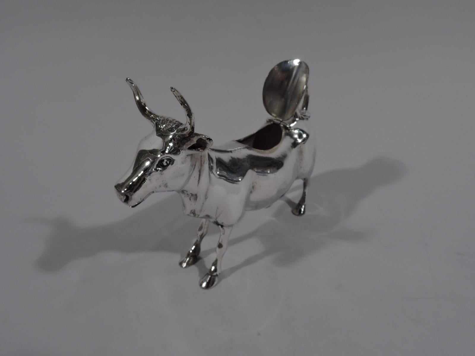 Traditional sterling silver cow creamer. Sturdy and thickset with prominent horns, flexed ears, and gaping mouth spout. Hinged back cover and flicked-back tail handle. Stiffened forelegs suggest bovine intractability. Marked “Sterling”. Also stamp