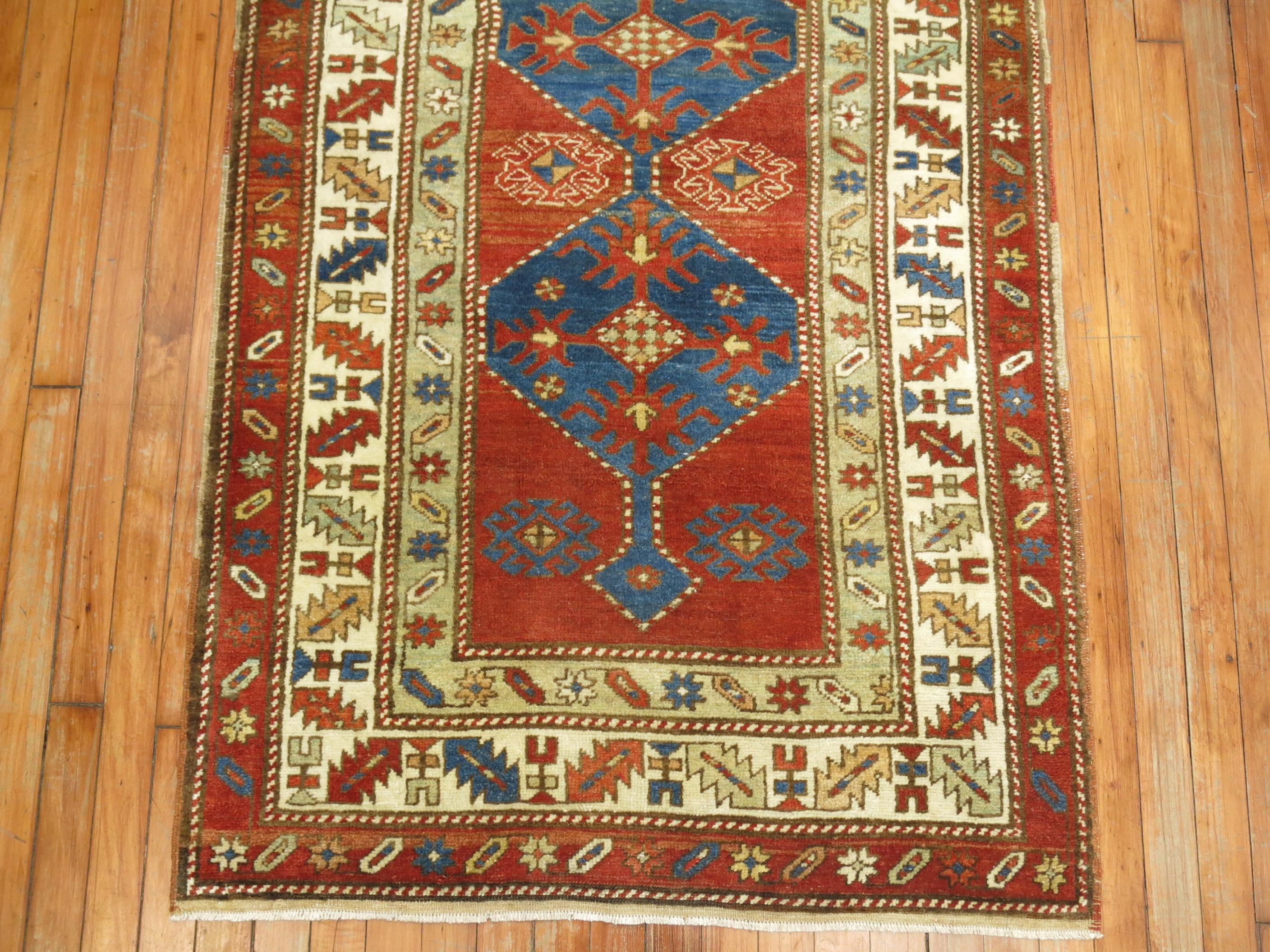 Geometric antique northwest Persian runner with a rusty brown field bodied by blue geometric medallions and a multi band border

Measures: 3'3” x 12'5”.